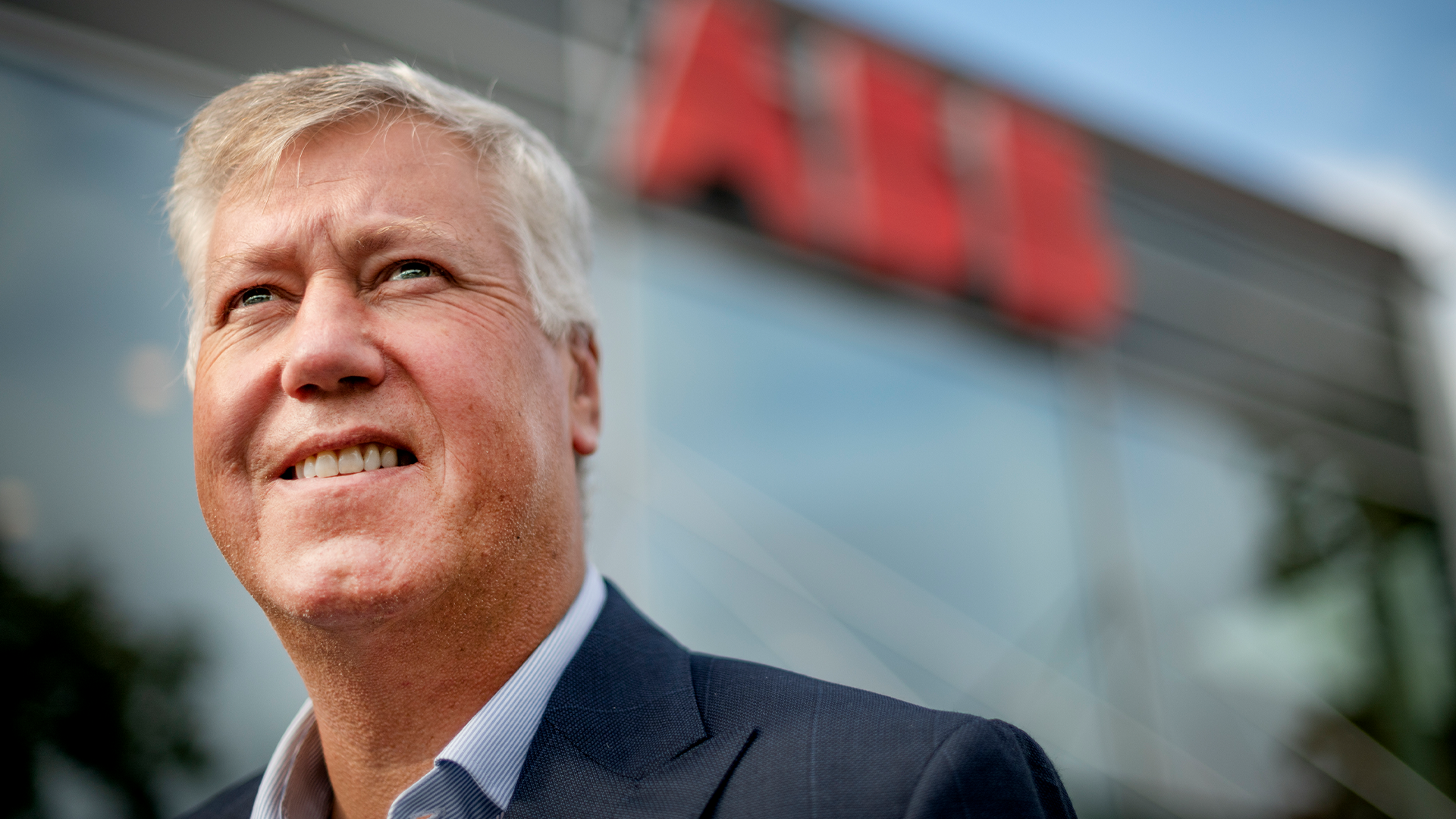 Porträtt av en man i mörk kavaj framför en byggnad med ABB-logon.