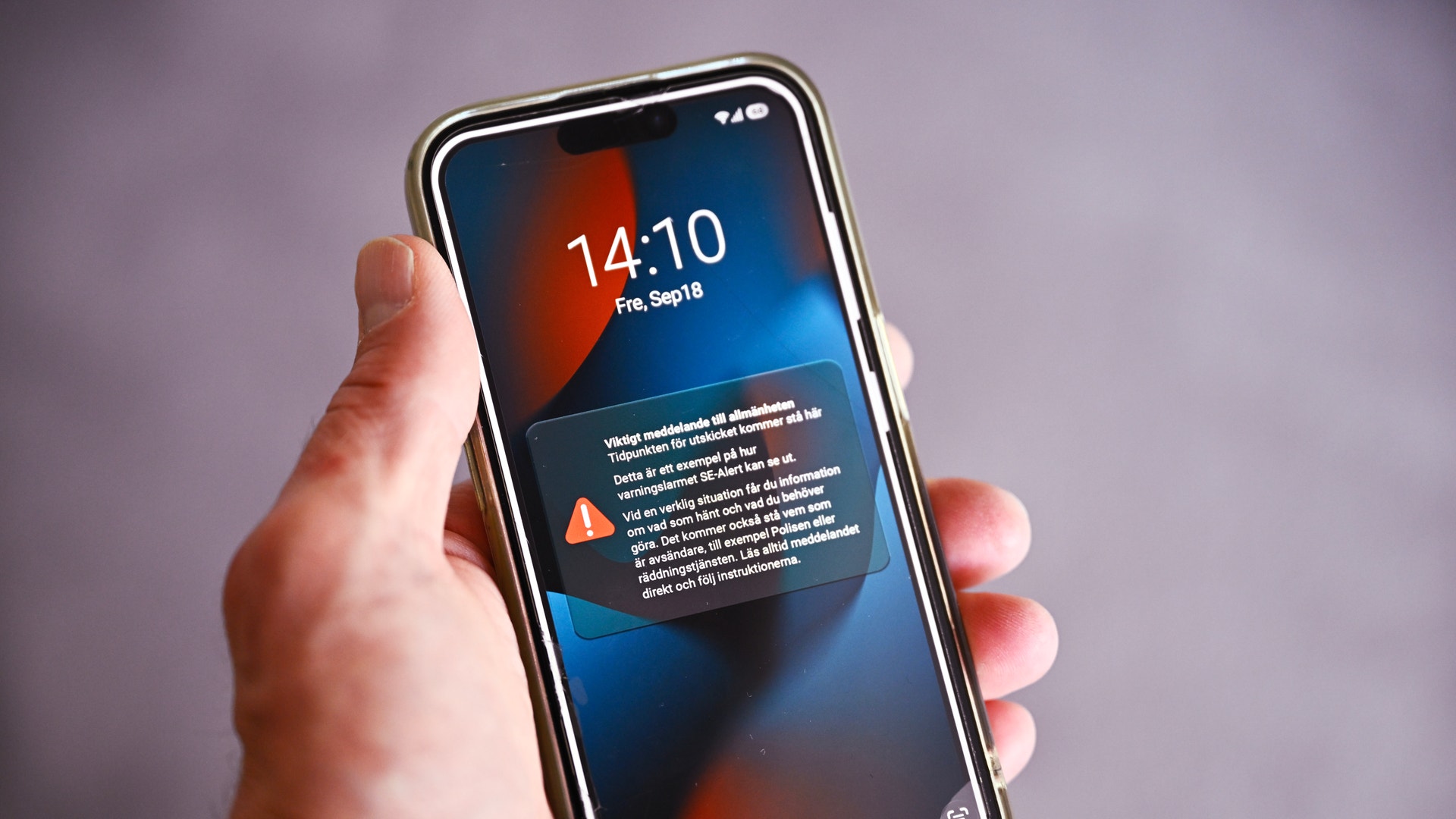 En hand håller en smartphone som visar en varningsmeddelande på skärmen.