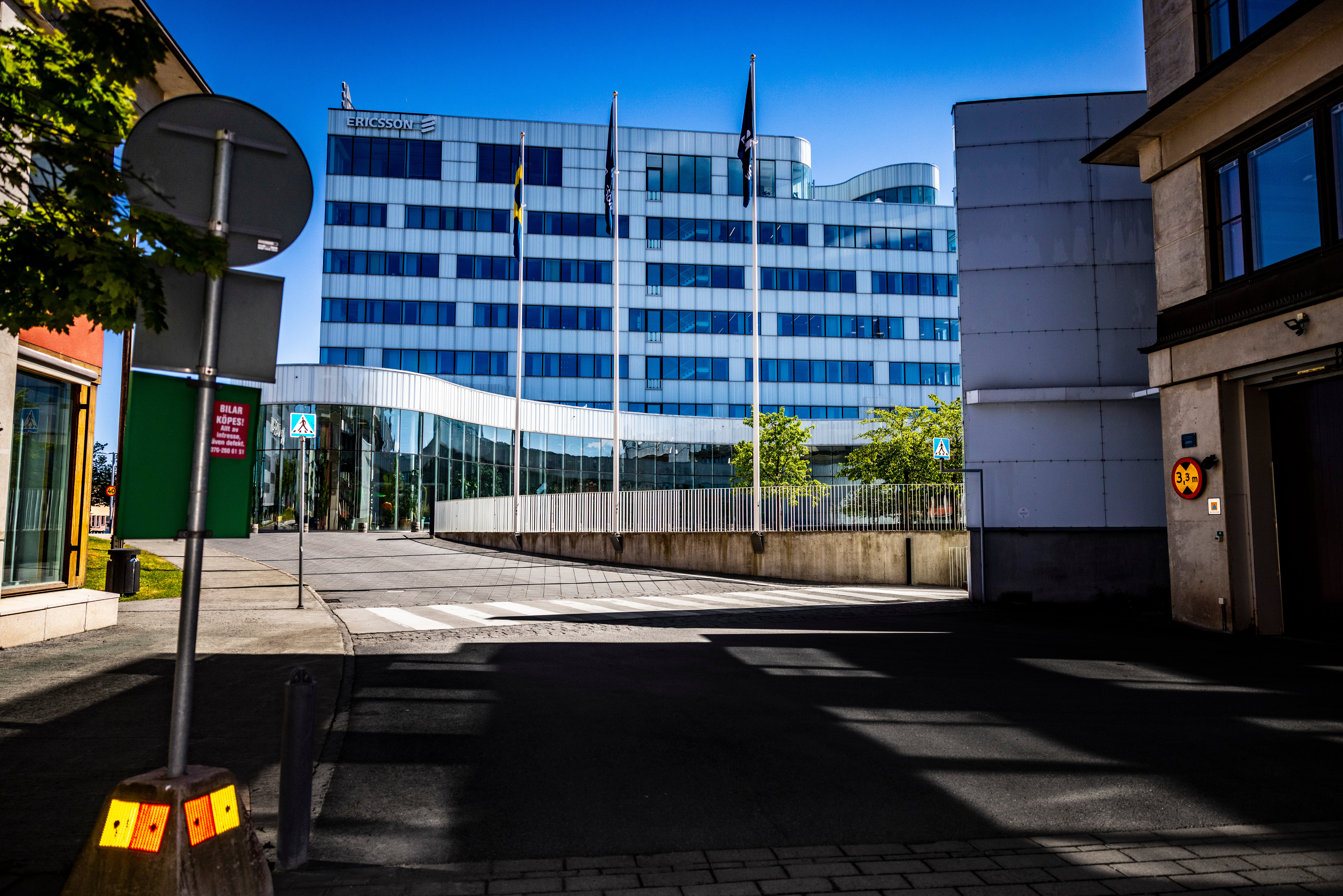 En modern blå kontorsbyggnad sett från en stadsgata med träd och andra byggnader omkring.