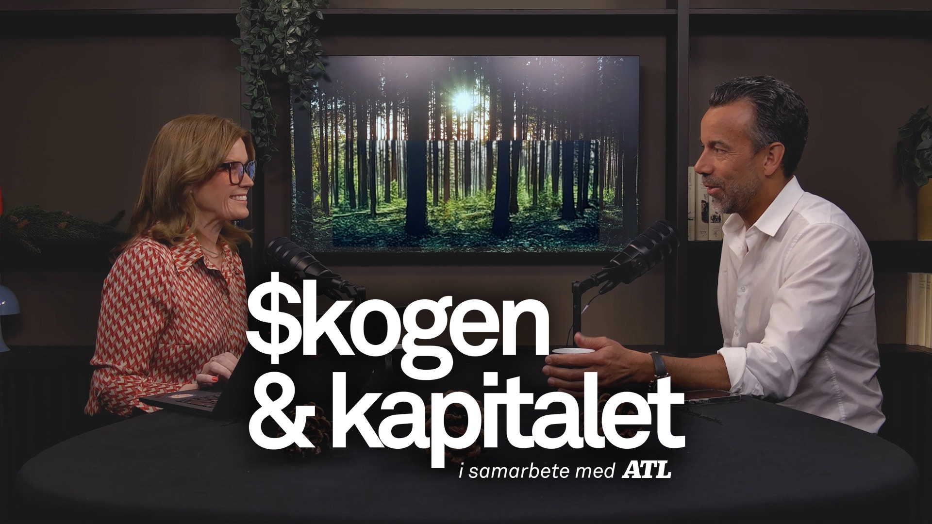 Två personer sitter och samtalar framför en skärm som visar en skog. Text på bilden läser 'skogen & kapitalet i samarbete med ATL'.