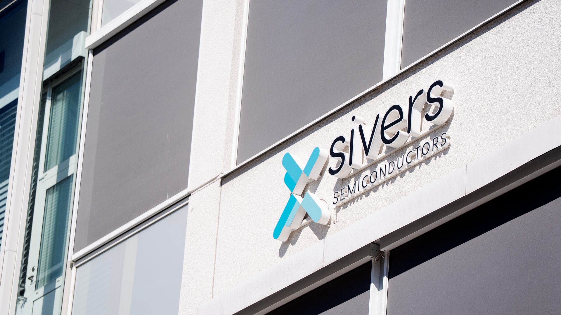 Fasad på en byggnad med Sivers Semiconductors logotyp och företagsnamn på en vit skylt.