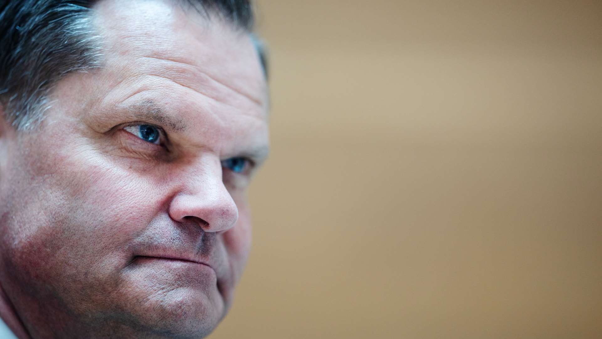 Porträttfoto av en man i profil mot neutral bakgrund.