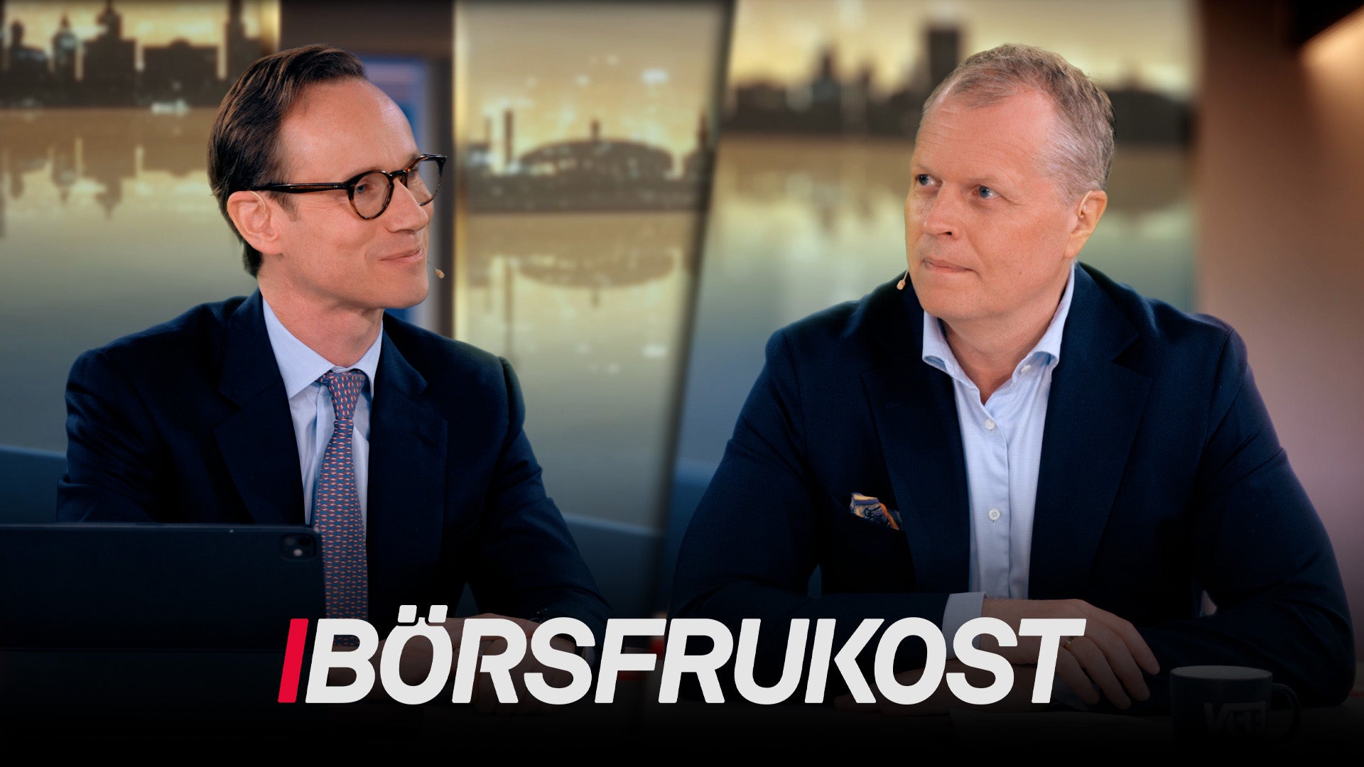 Två män sitter vid ett bord i en TV-studio och diskuterar. I bakgrunden syns stadsbilder. Texten Börsfrukoost visas längst ned på skärmen.