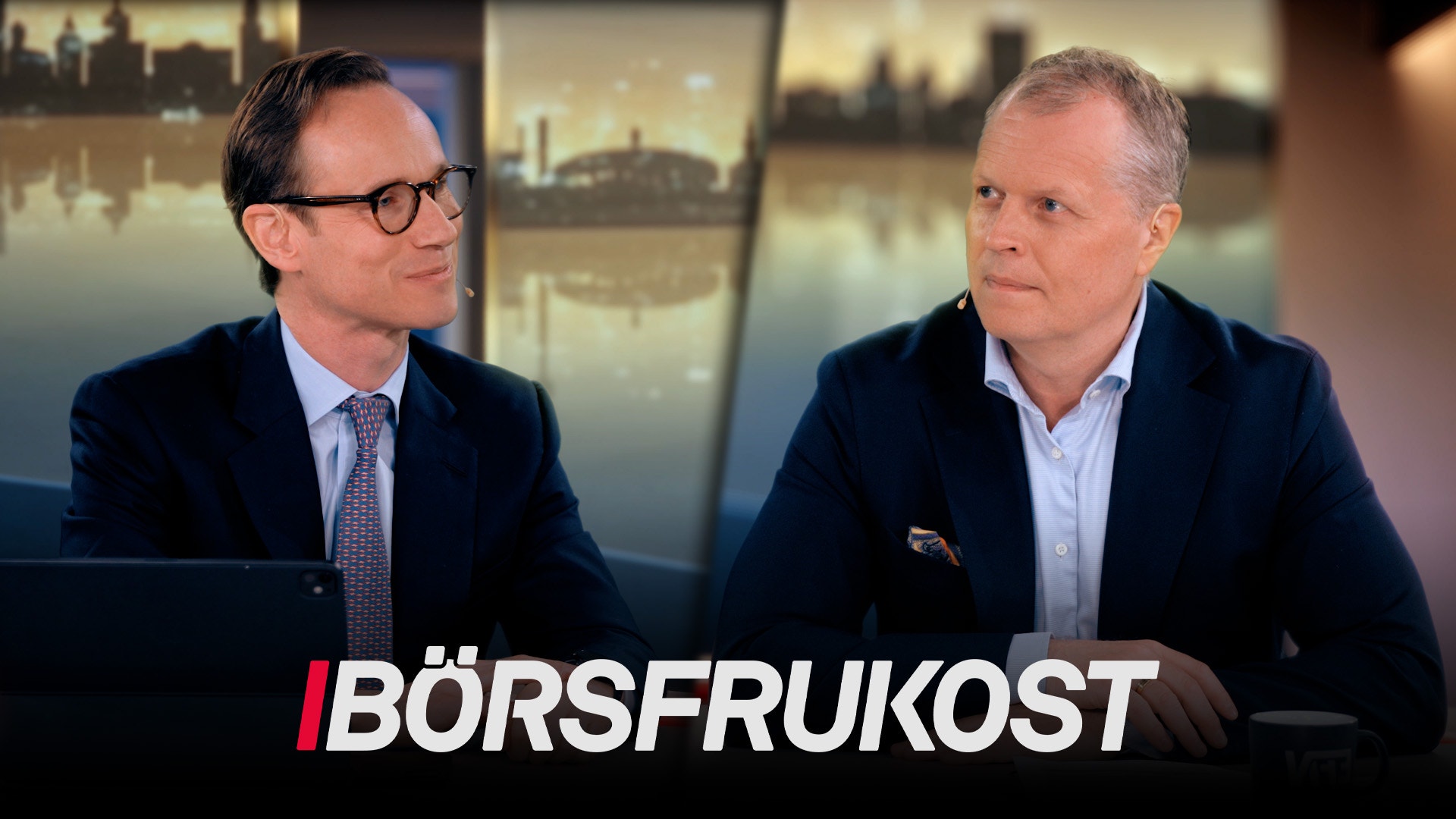Två män sitter vid ett bord i en TV-studio och diskuterar. I bakgrunden syns stadsbilder. Texten Börsfrukoost visas längst ned på skärmen.