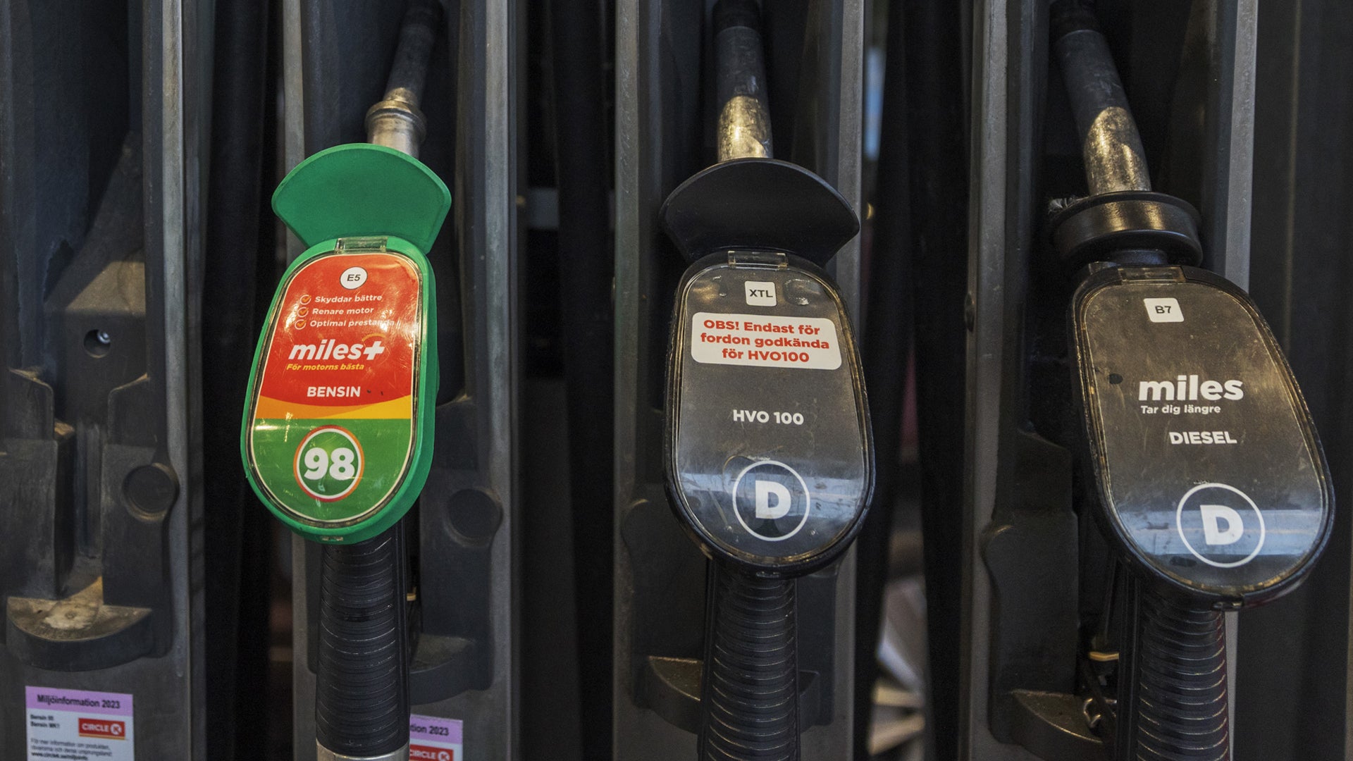 Bränslepumpar vid en bensinstation med olika bränsletyper märkta på handtagen