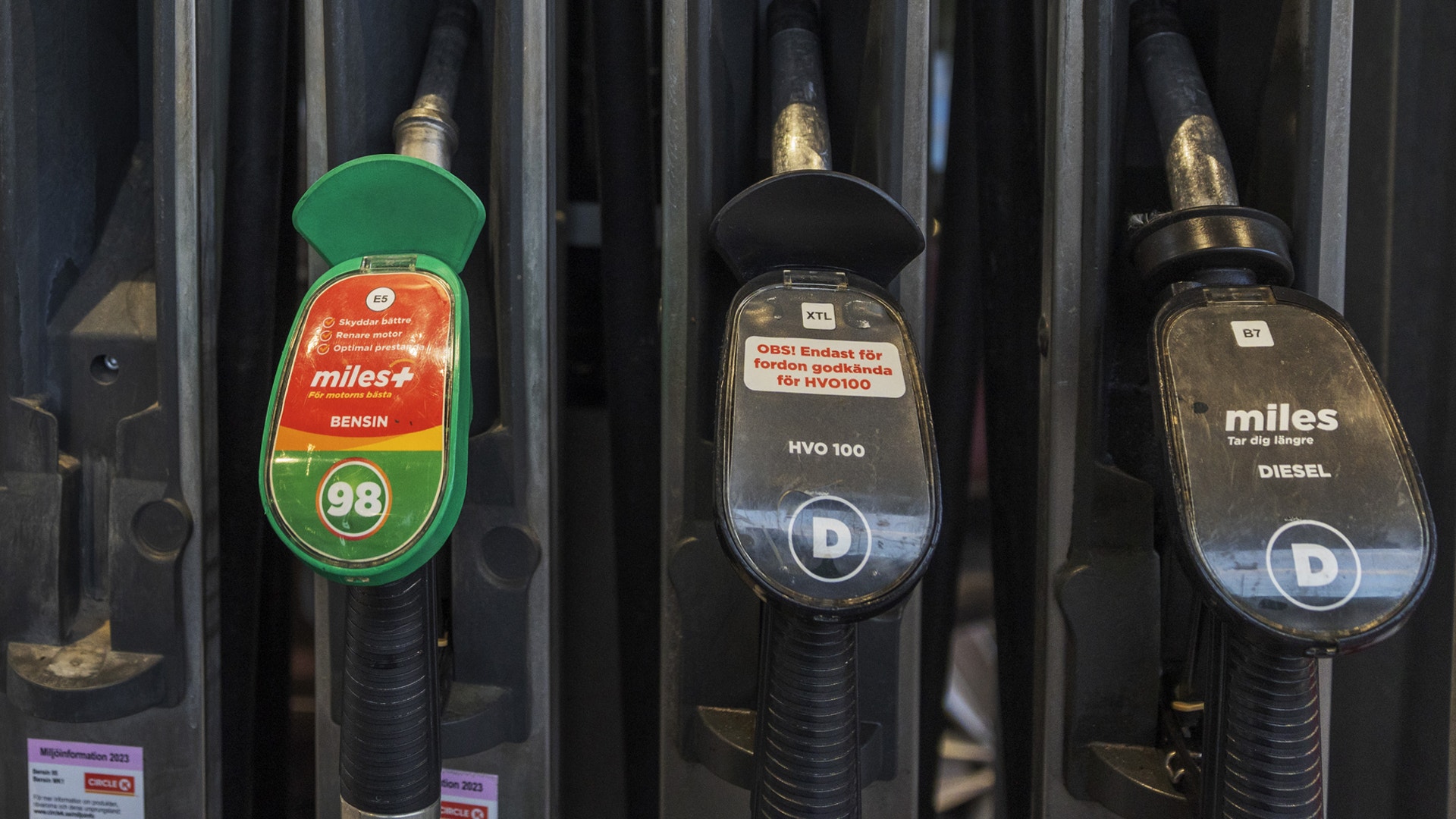 Bränslepumpar vid en bensinstation med olika bränsletyper märkta på handtagen