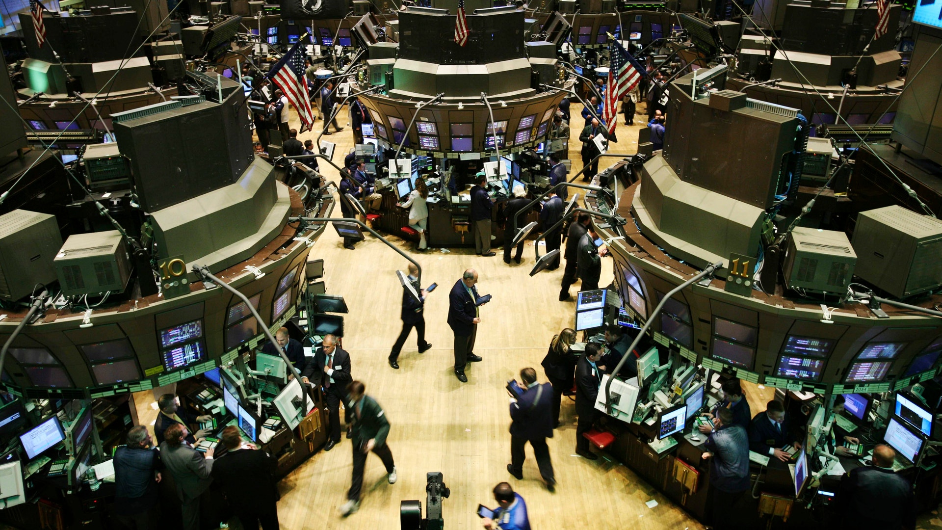 Handelsgolvet på New York Stock Exchange med handlare vid sina arbetsplatser och amerikanska flaggor.