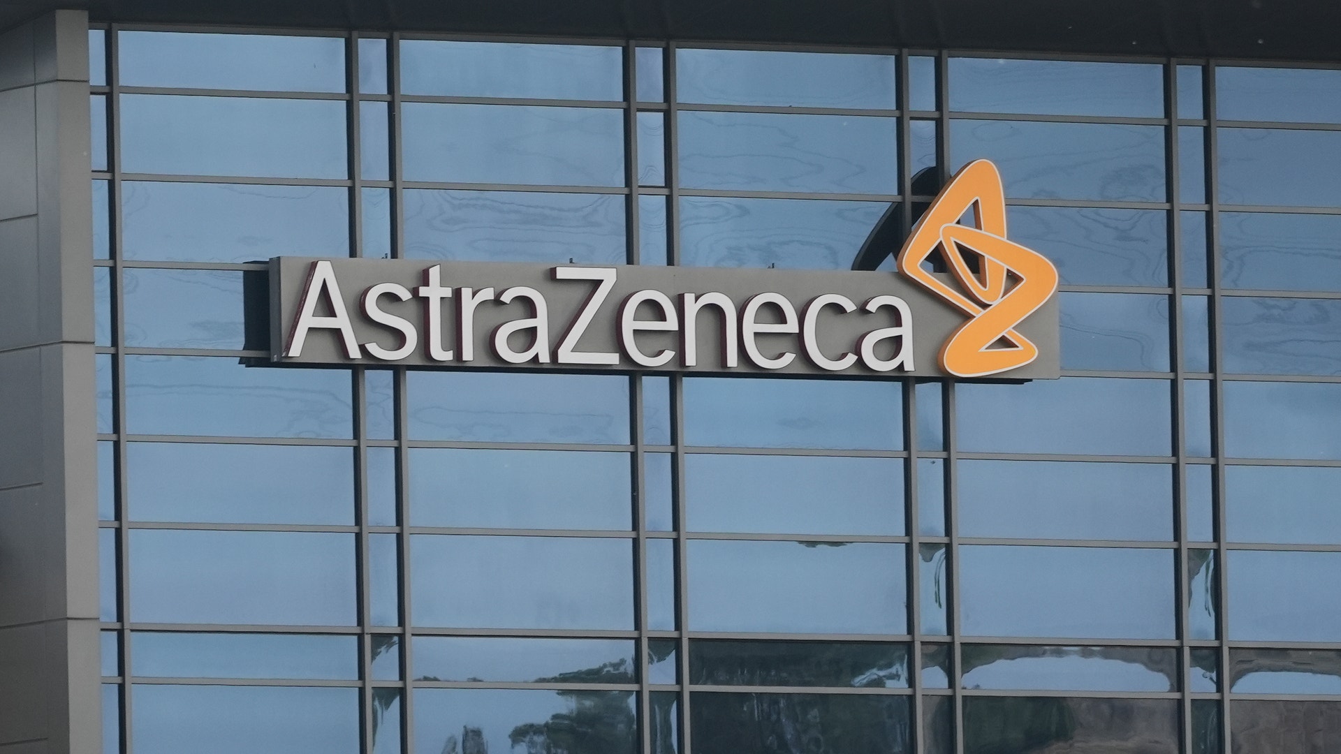 AstraZenecas företagslogga på en byggnadsfasad med stora fönster.