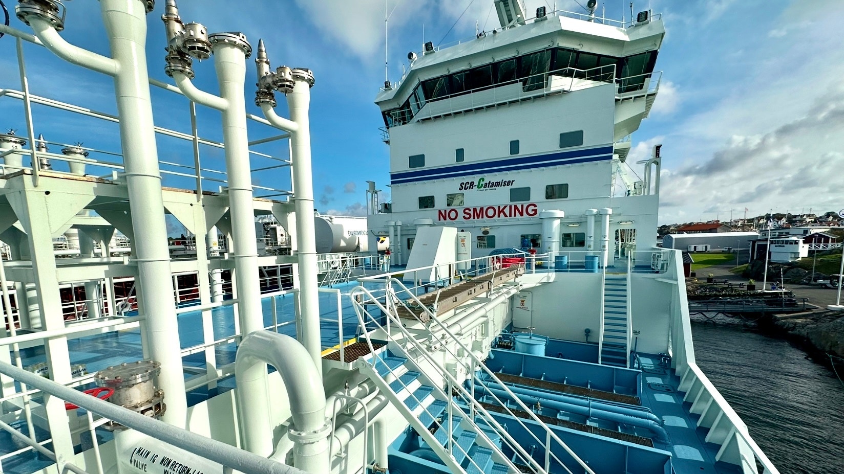 En stor passagerarfärja eller kryssningsfartyg dockat vid en hamn med vita räcken och blå detaljer synliga på skeppet.