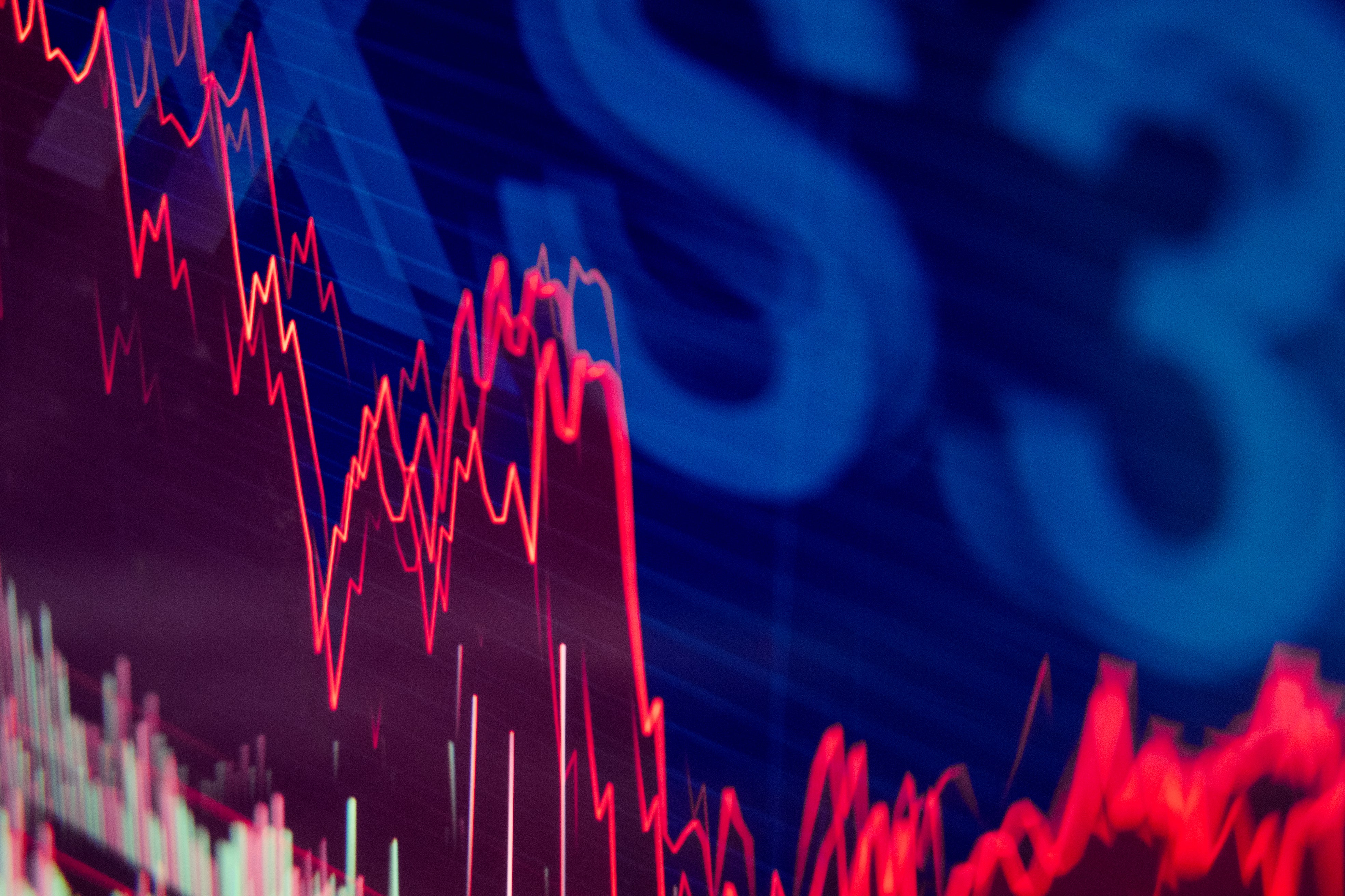 Finansiell graf med röda nedåtgående trendlinjer på blå bakgrund, symboliserar aktiemarknadens nedgång.