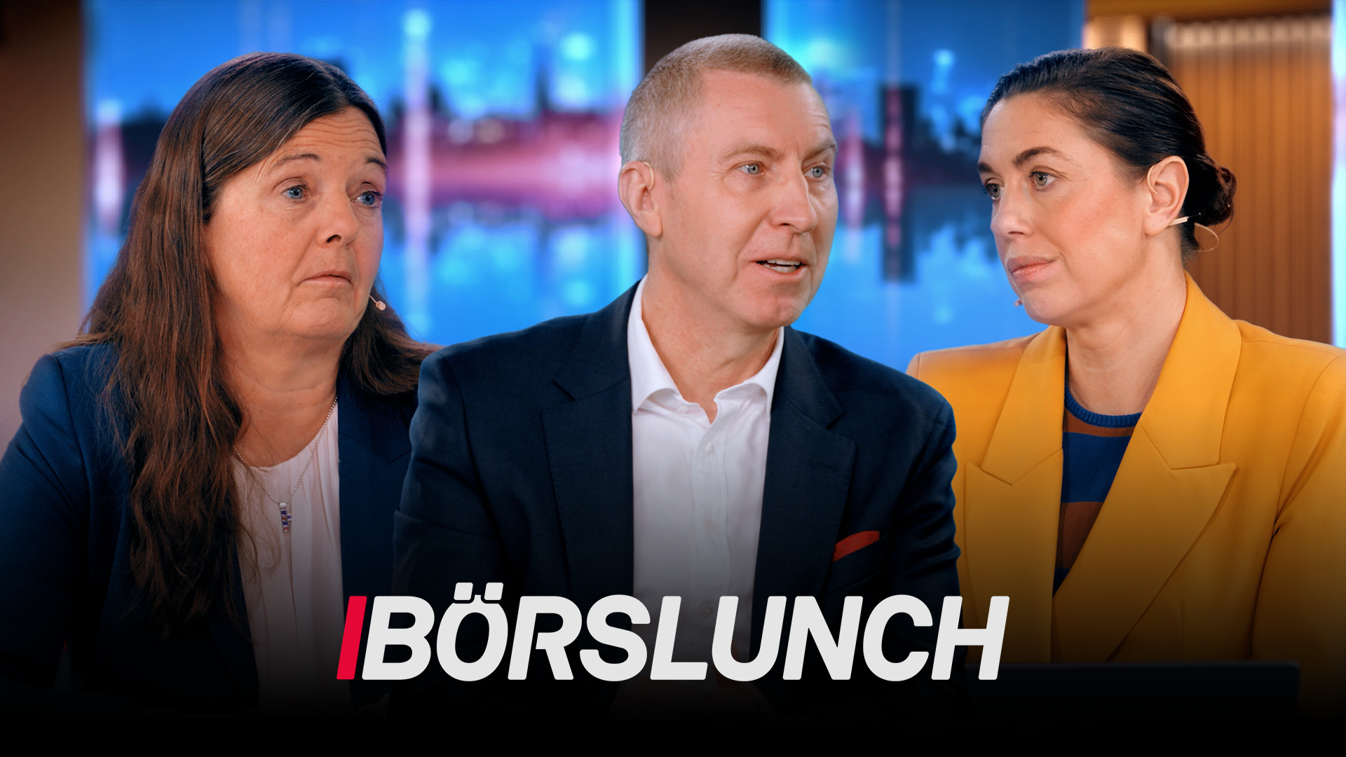 Två kvinnor och en man i kavajer tittar mot varandra i en tv-studio. Nederst syns programlogotypen Börslunch.