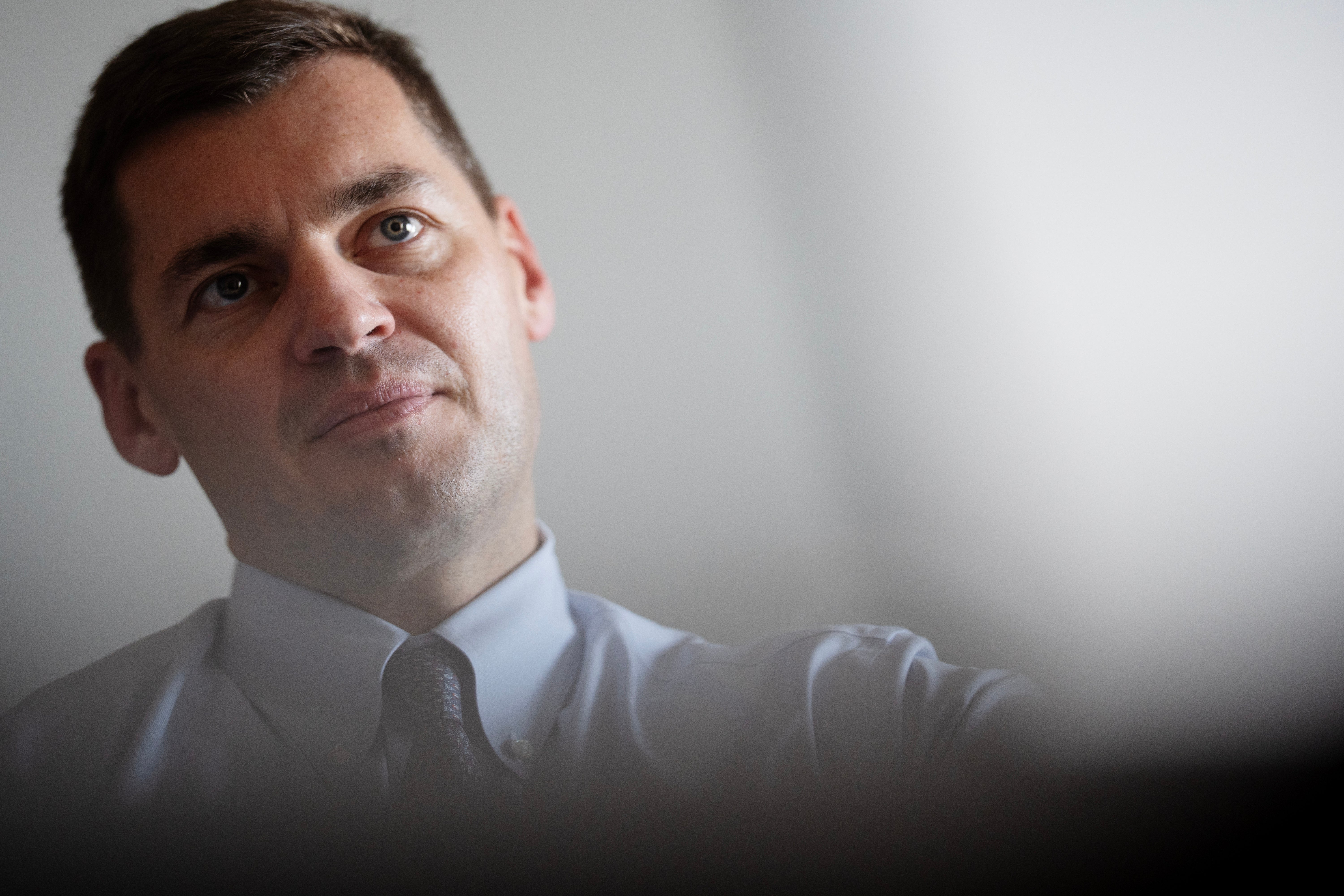 Porträtt av en man i vit skjorta och slips mot neutral bakgrund.
