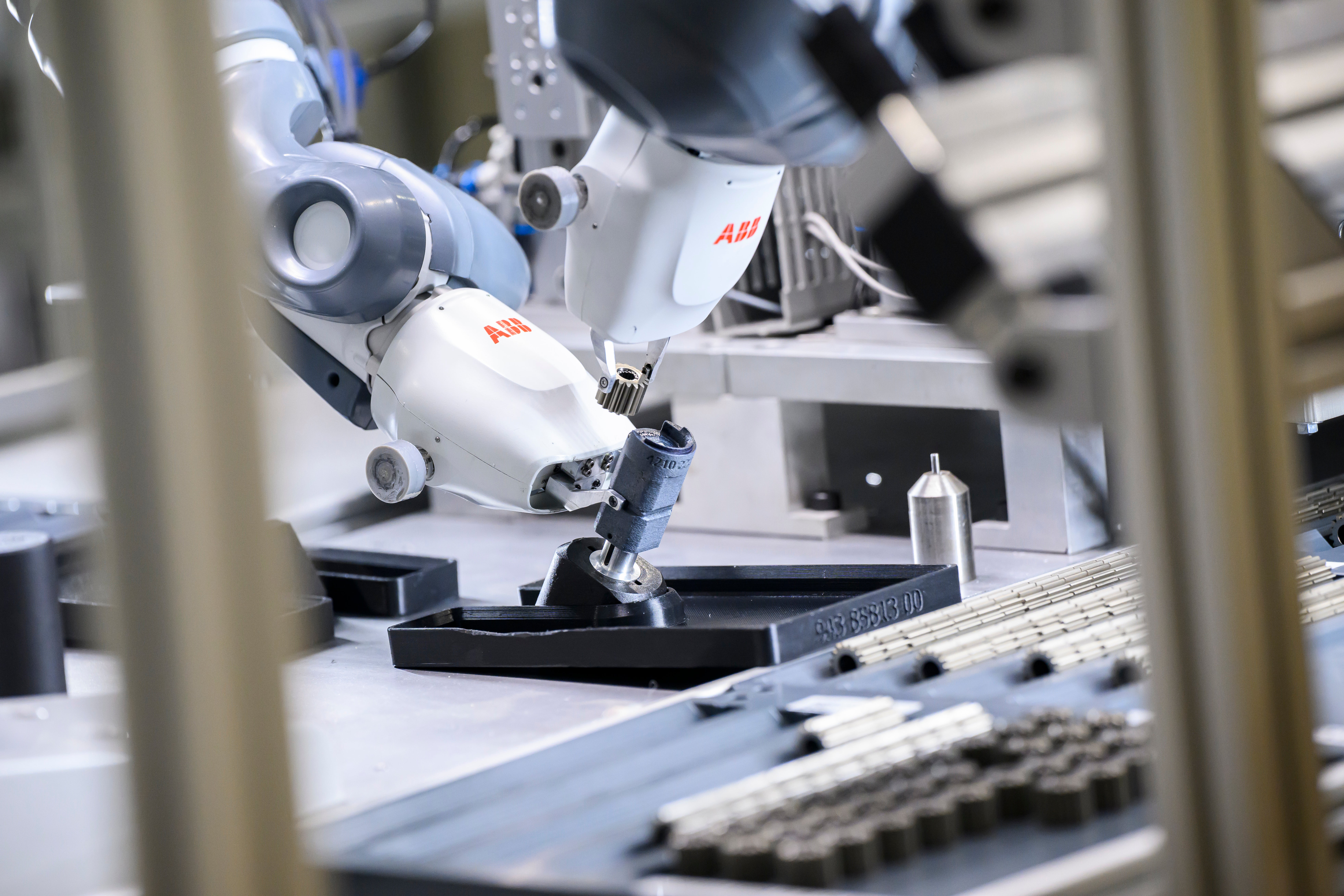 En vit och blå industrirobot från ABB monterar elektroniska komponenter på ett arbetsbord.