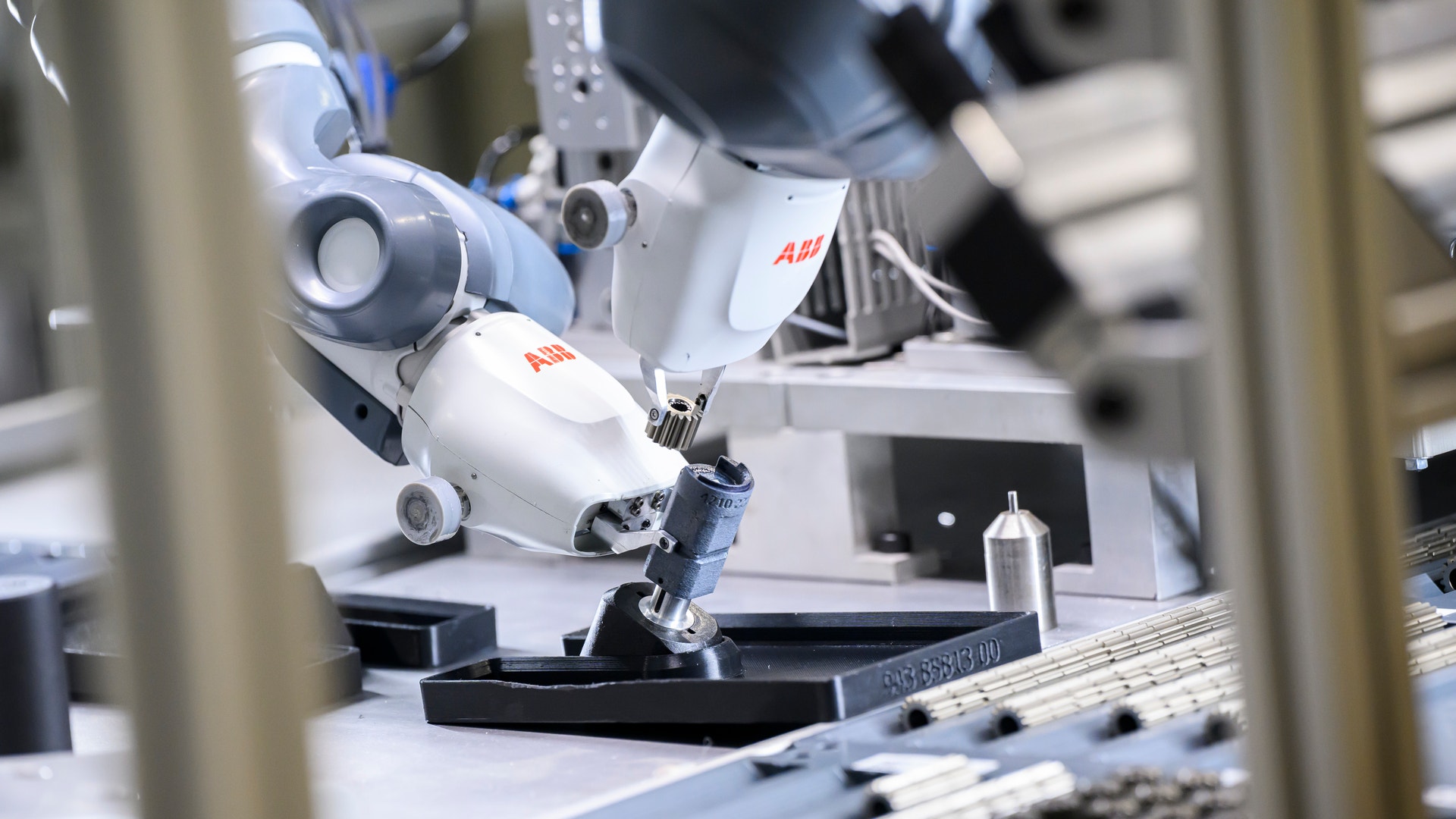 En vit och blå industrirobot från ABB monterar elektroniska komponenter på ett arbetsbord.