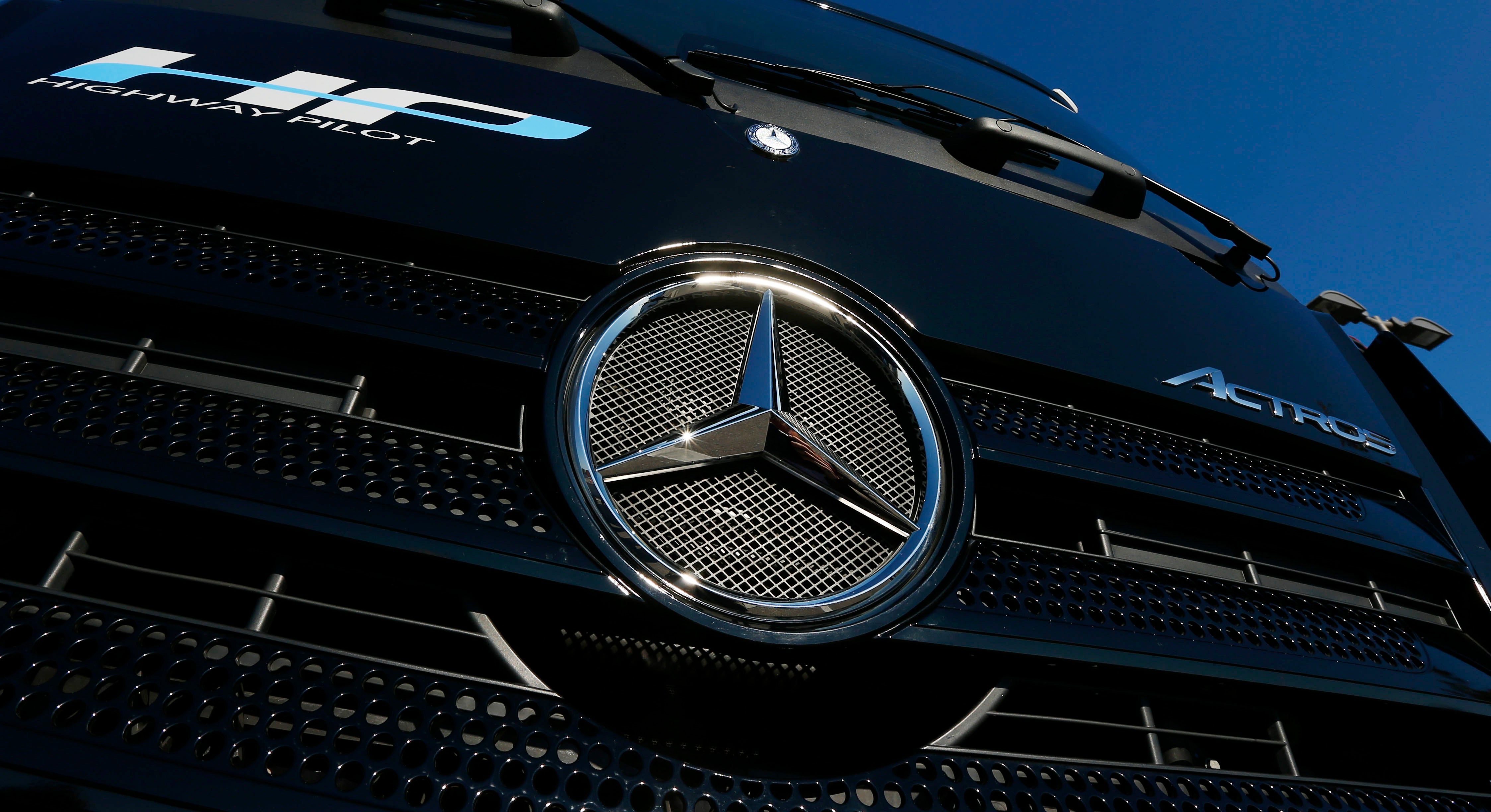 Närbild på Mercedes-Benz lastbils grille med den karakteristiska trestjärniga logotypen mot blå himmel.