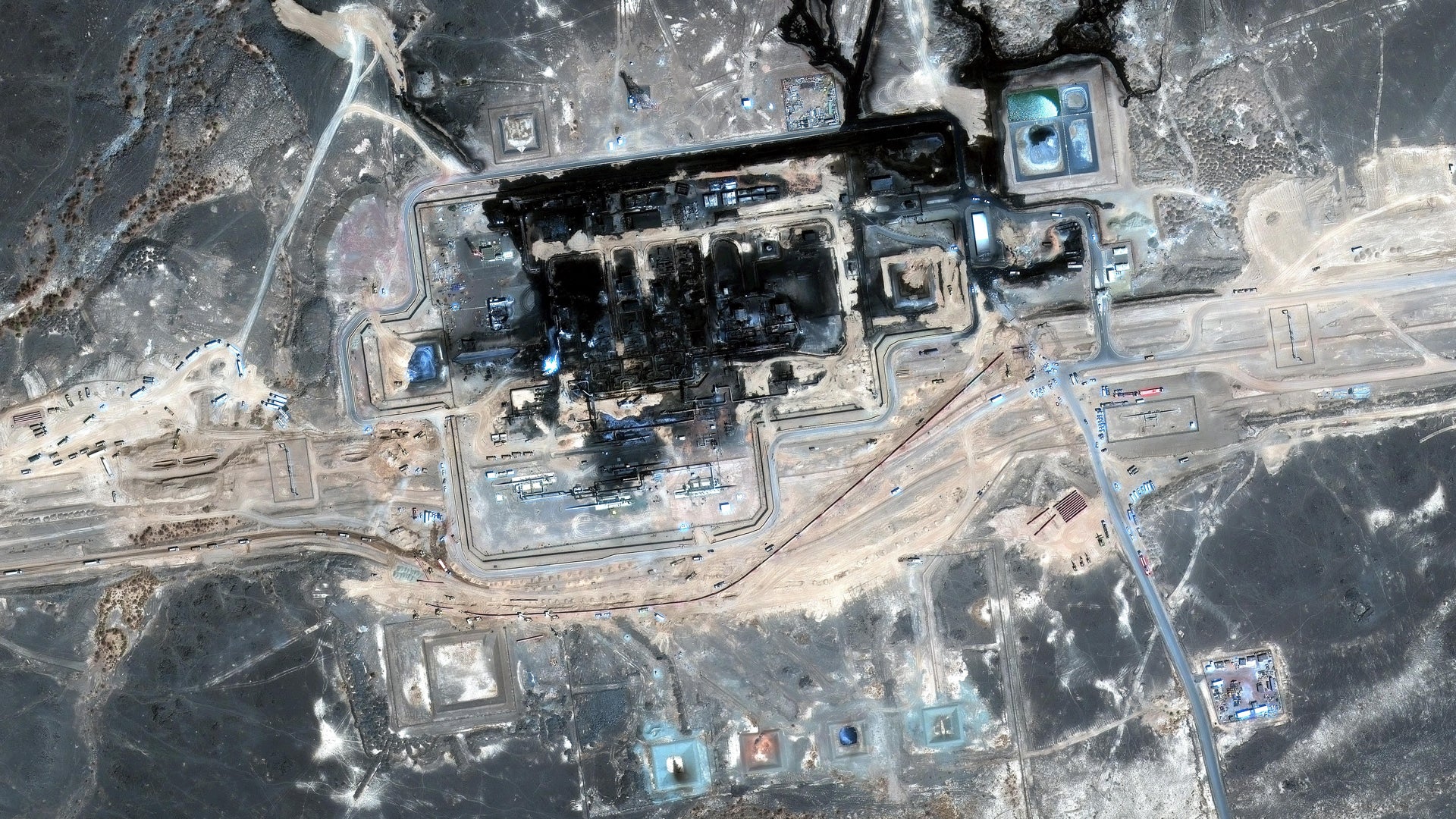 Satellitbild av ett stort industriområde, troligen en gruv- eller kolanläggning, med byggnader, vägar och upplagsytor sett uppifrån.
