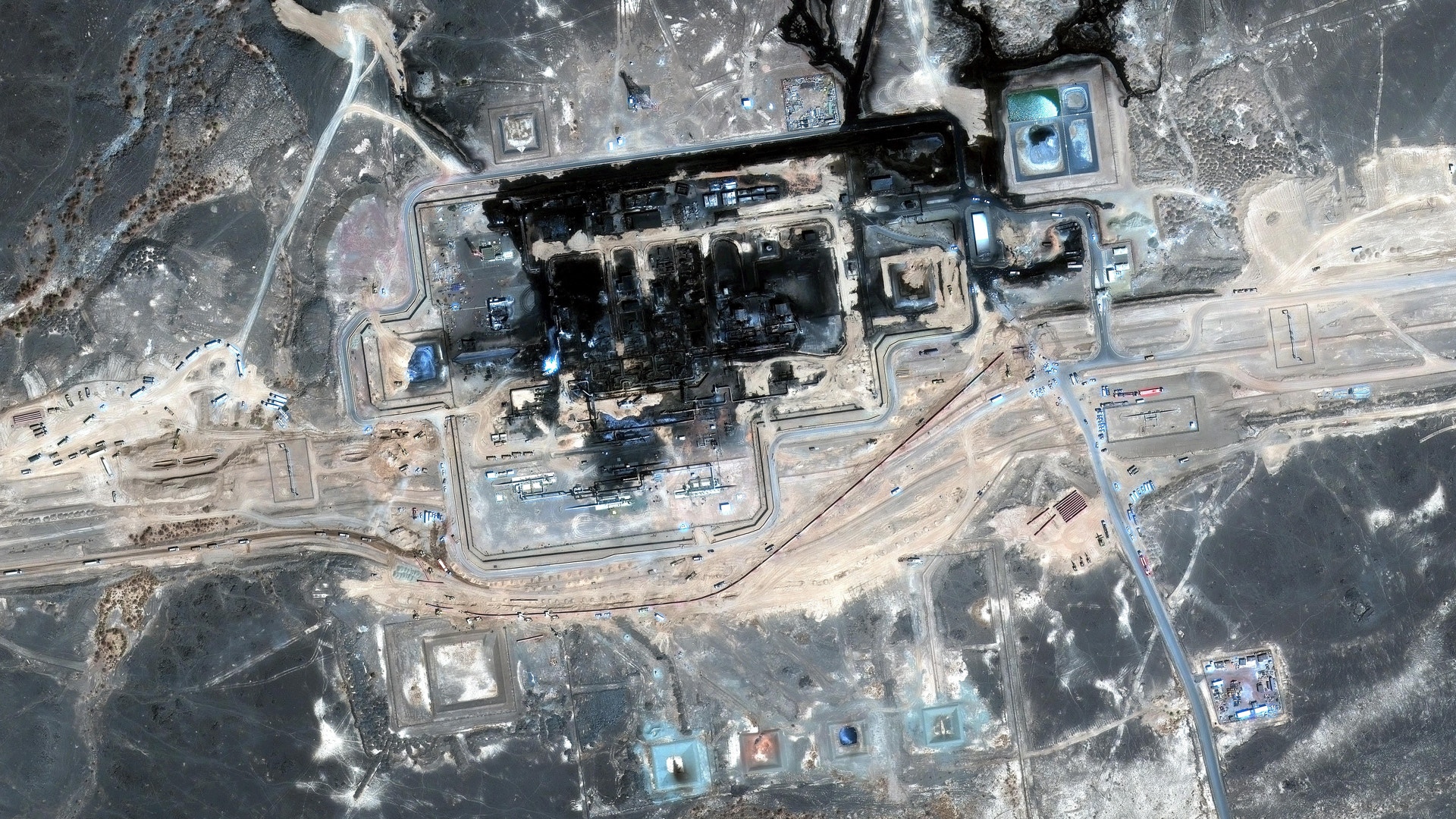 Satellitbild av ett stort industriområde, troligen en gruv- eller kolanläggning, med byggnader, vägar och upplagsytor sett uppifrån.