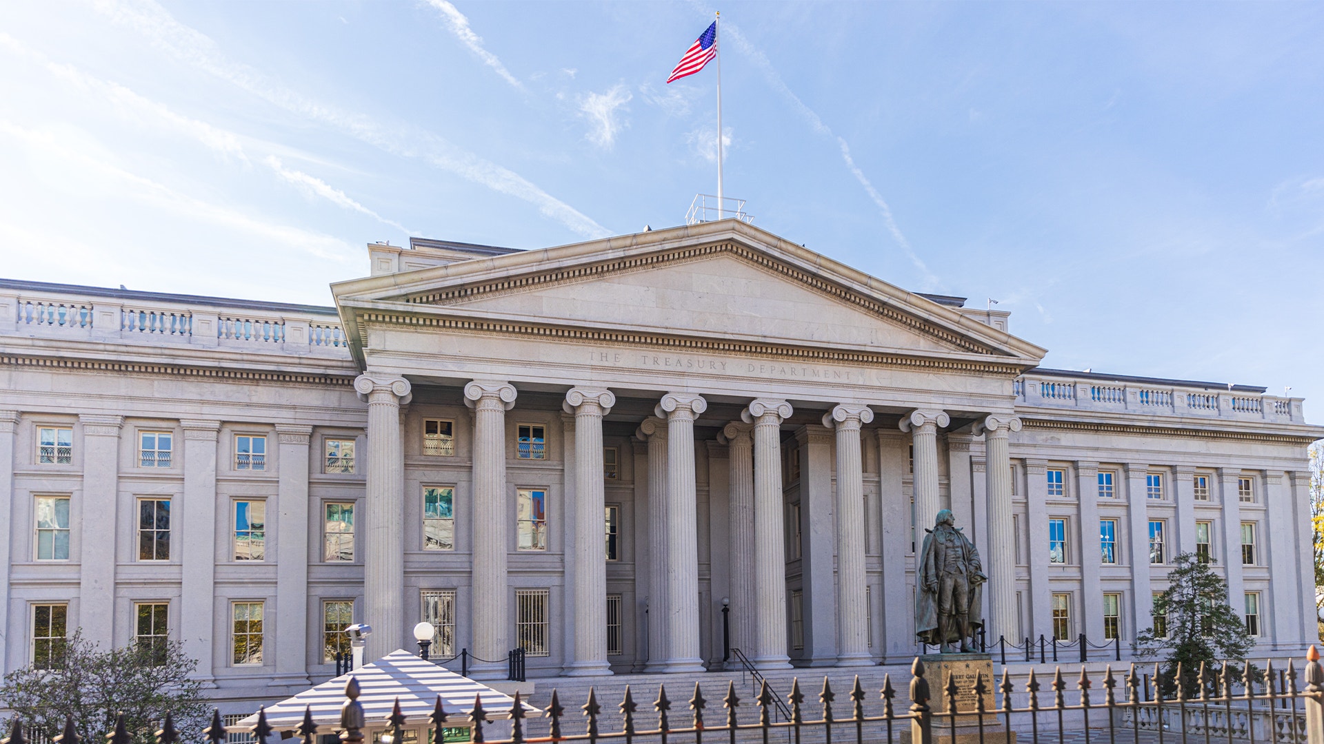 Amerikanska finansdepartementets byggnad i Washington, en stor ljus stenbyggnad med pelare och en flagga på taket.