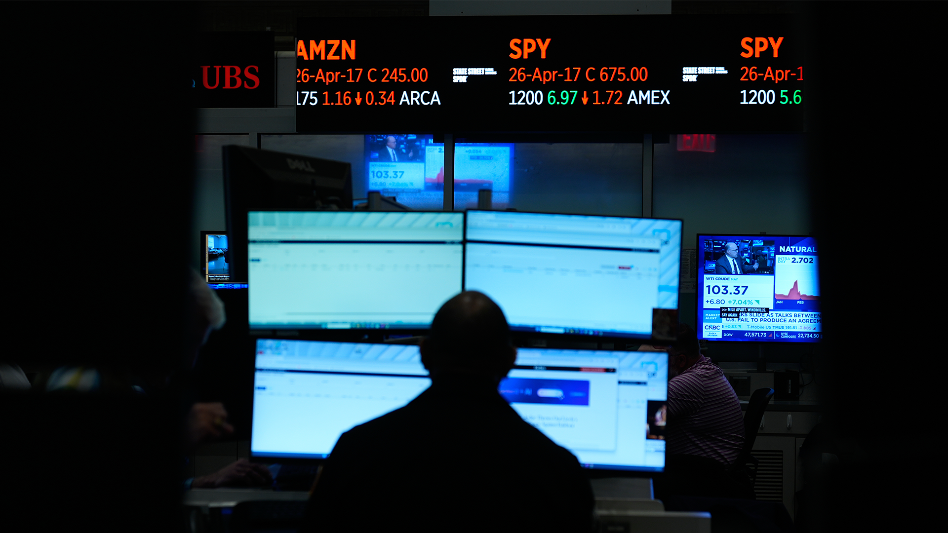 En trader sitter framför flera datorskärmar med aktiekurser och marknadsdata på Wall Street.