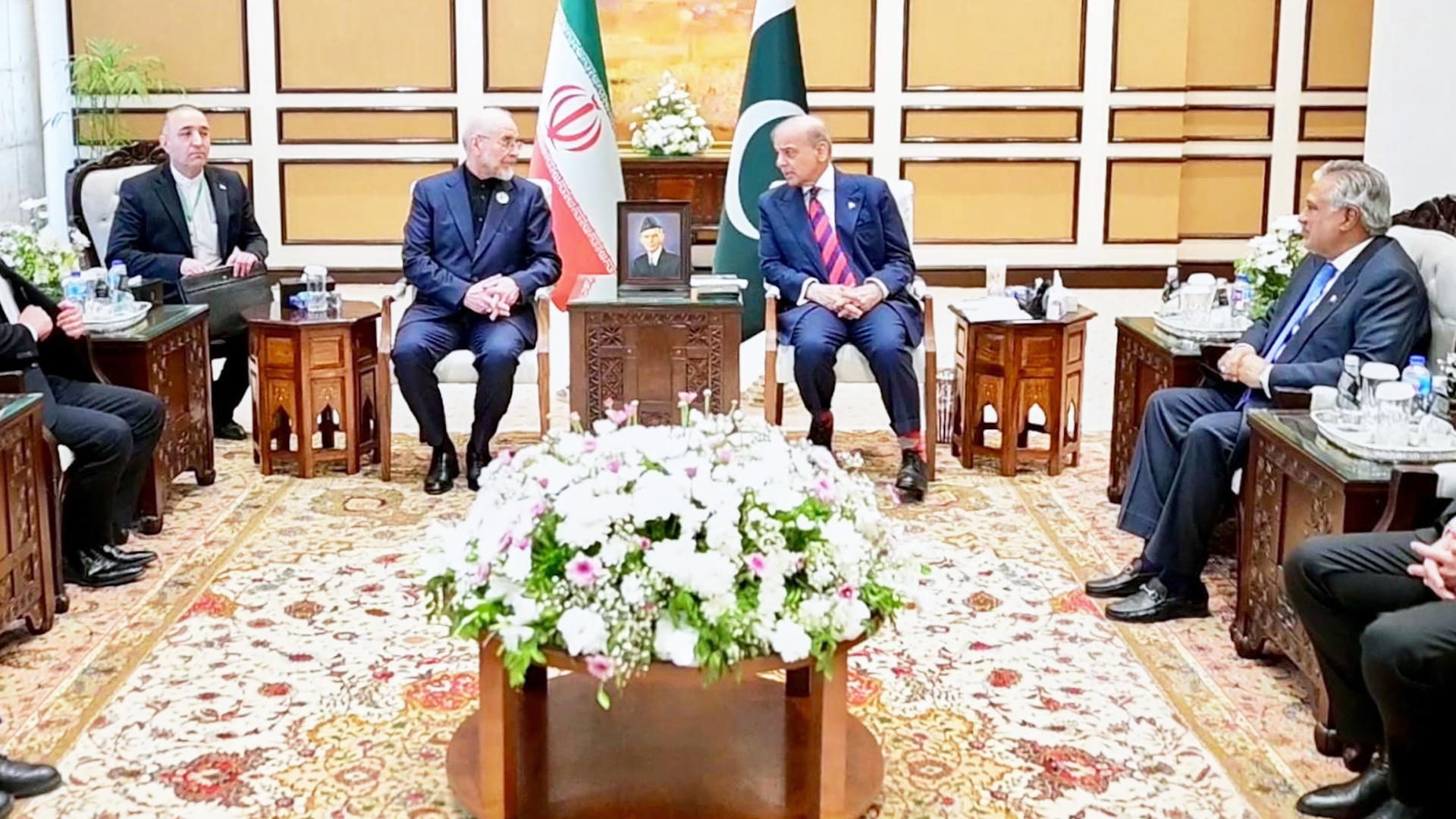 Formellt möte mellan diplomater och regeringsrepresentanter från Iran och Pakistan i en elegant sal med traditionell inredning och blomsterdekorationer.