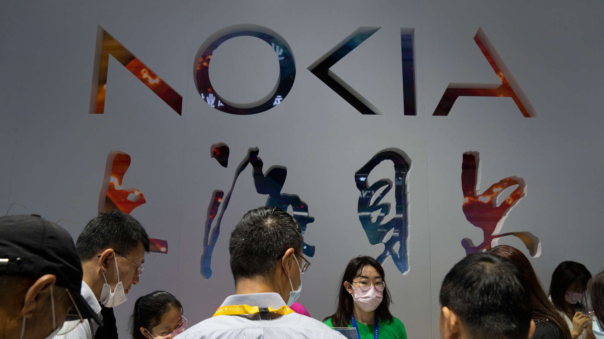 Grupp människor står framför en vägg med stora färgglada bokstäver som bildar ordet Nokia.