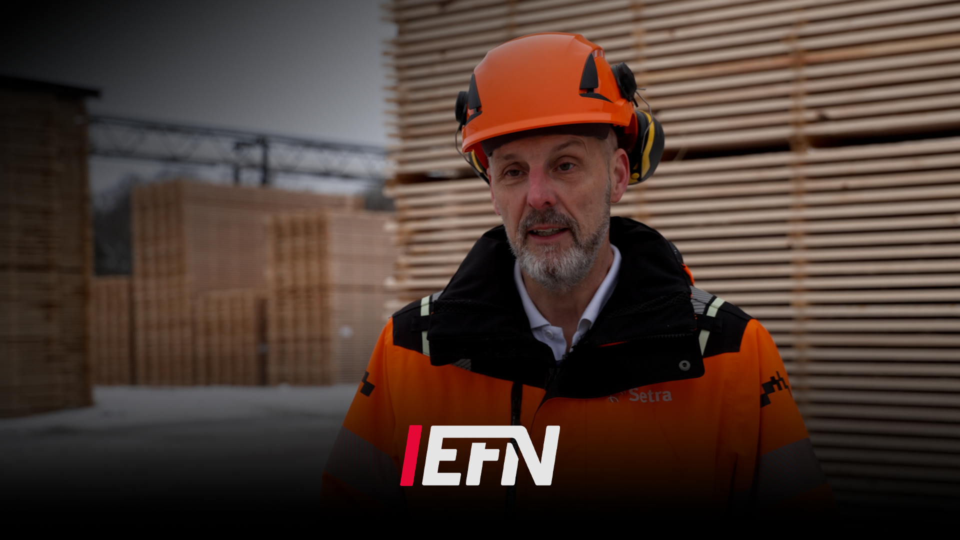 Man i orange säkerhetsutrustning vid ett sågverk