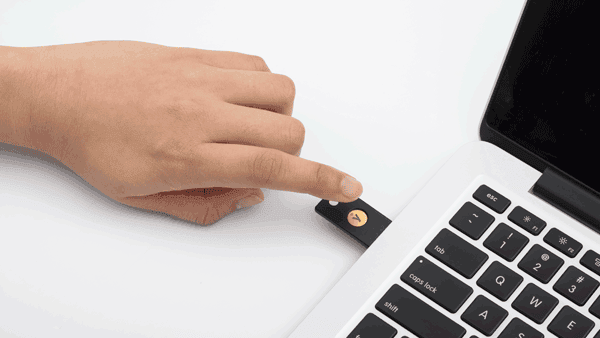 Hand som berör en NFC-tagg bredvid en laptop