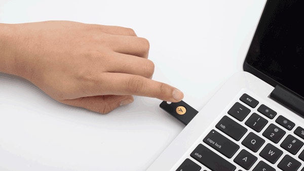 Hand som berör en NFC-tagg bredvid en laptop