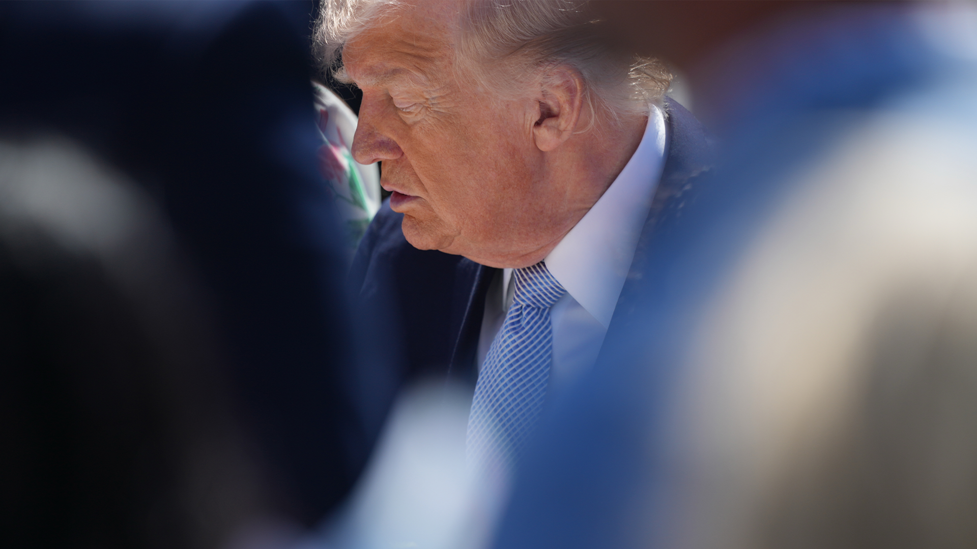 Porträttfoto av en man i blå skjorta och slips, fotograferad i profil mot en suddig bakgrund.