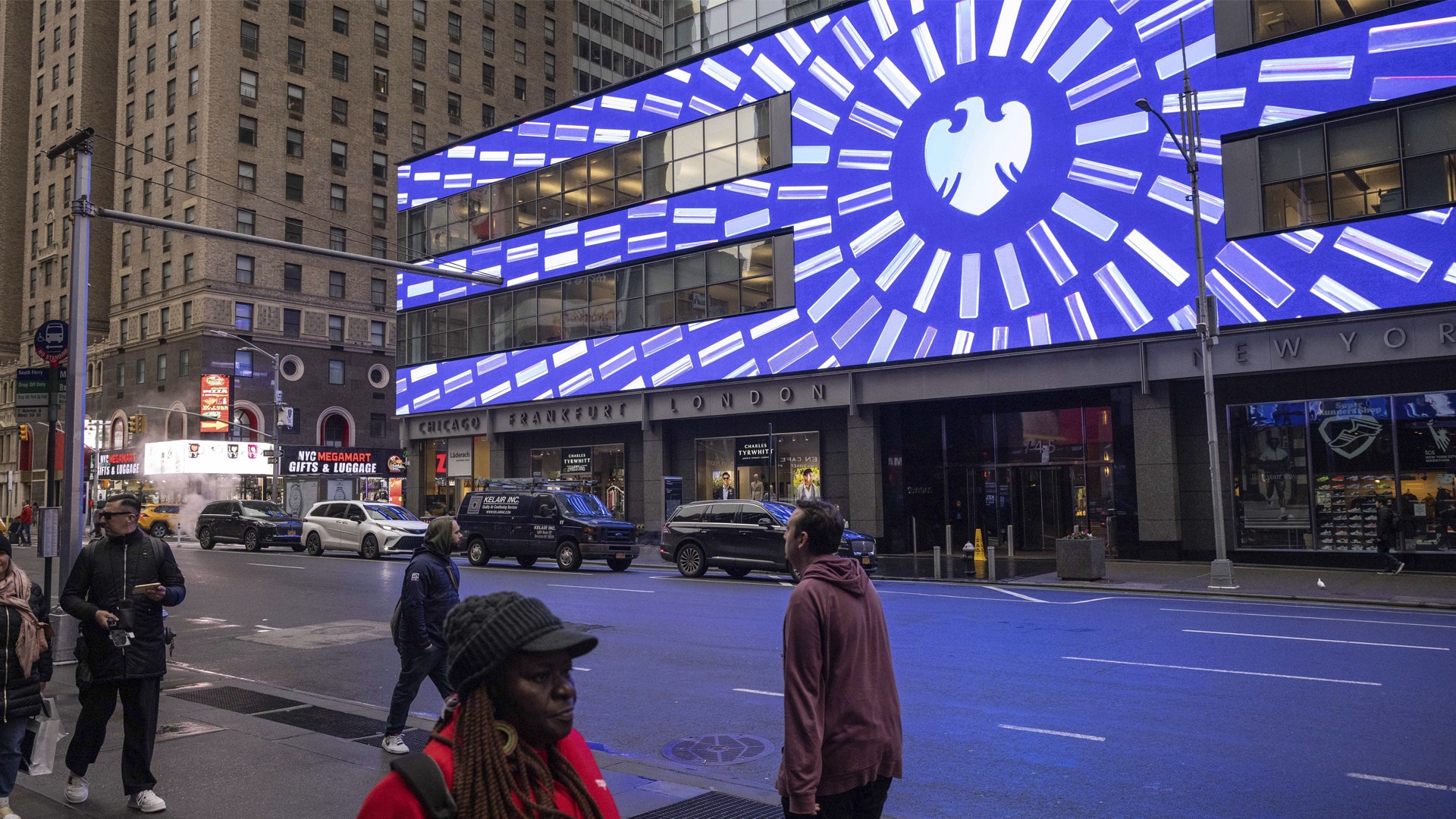 Gatuscen med en stor blå upplyst klockdisplay på en byggnadsfasad