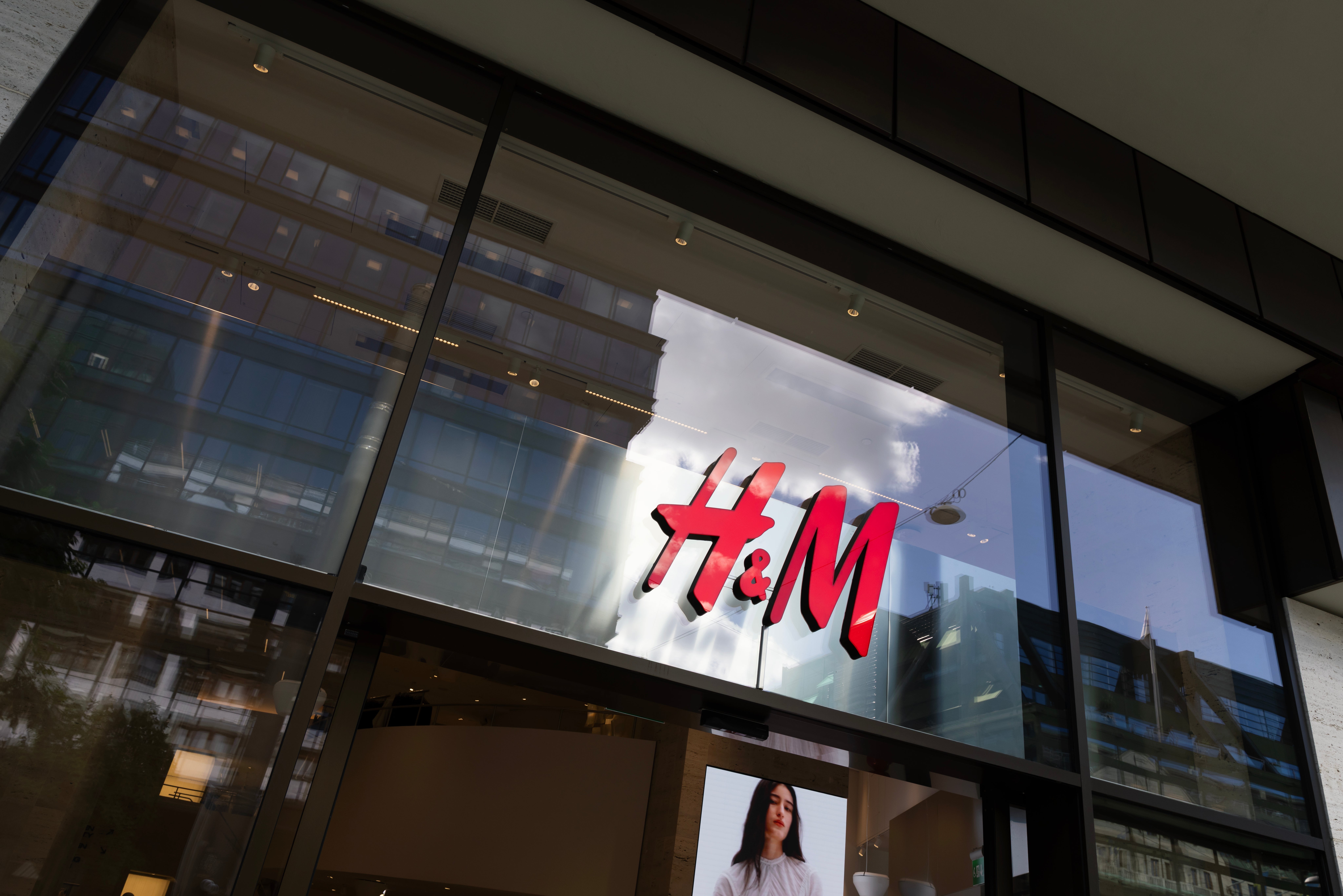 H&M-butikens fasad med röd logotyp på upplyst skylt