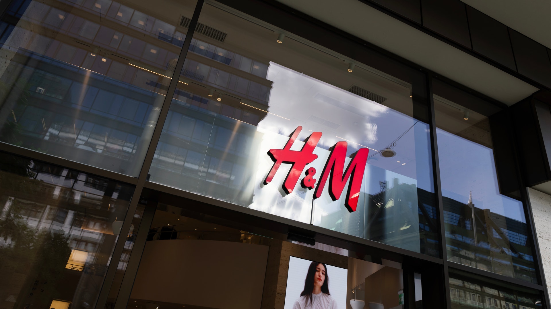 H&M-butikens fasad med röd logotyp på upplyst skylt