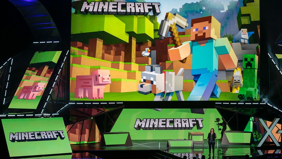 Minecraft-spel visas på stor skärm med ikoniska blockkonstruerade karaktärer och landskap på en event-scen.