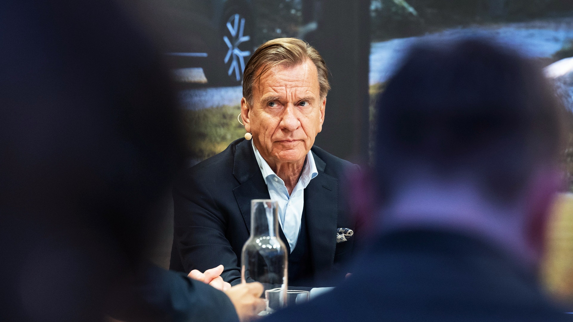Håkan Samuelsson, klädd i mörk kavaj, sitter vid ett bord och tittar allvarligt åt sidan under ett möte.