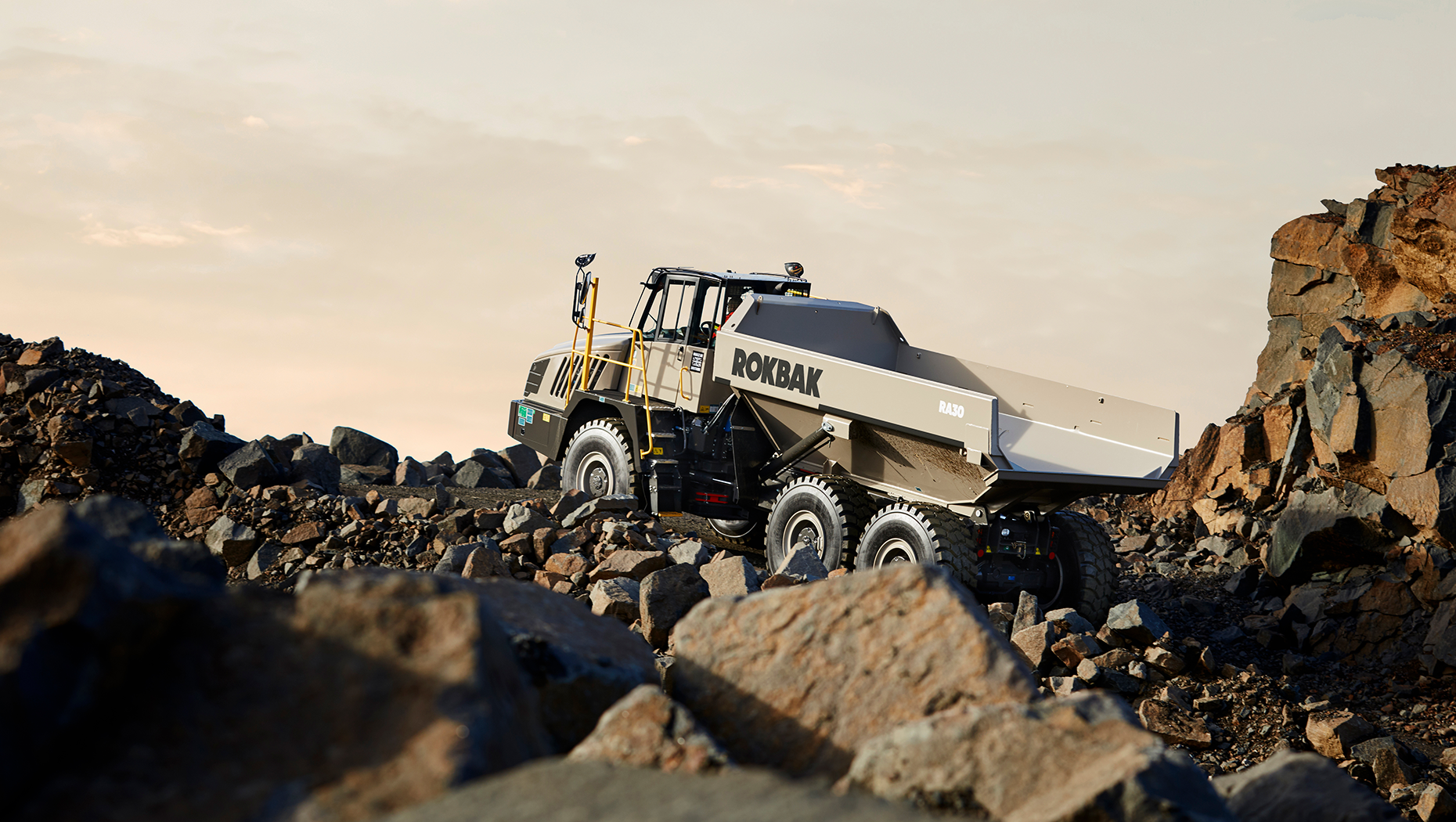 En stor lastbil navigerar genom stenig terräng med stora stenar