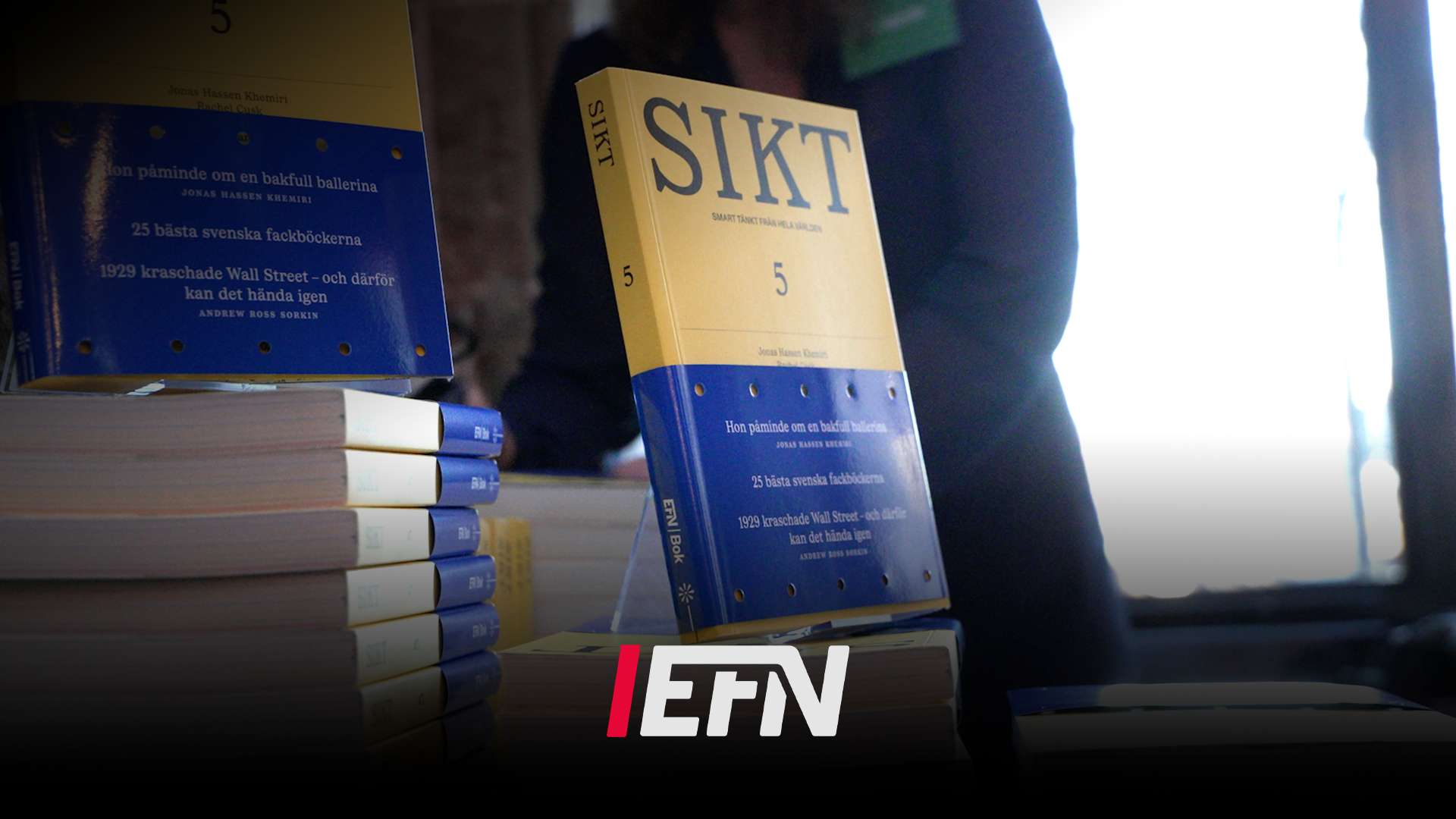 Bok med titeln SIKT nummer 5, blå och gul omslag, fotograferad tillsammans med flera staplade exemplar av samma bok.