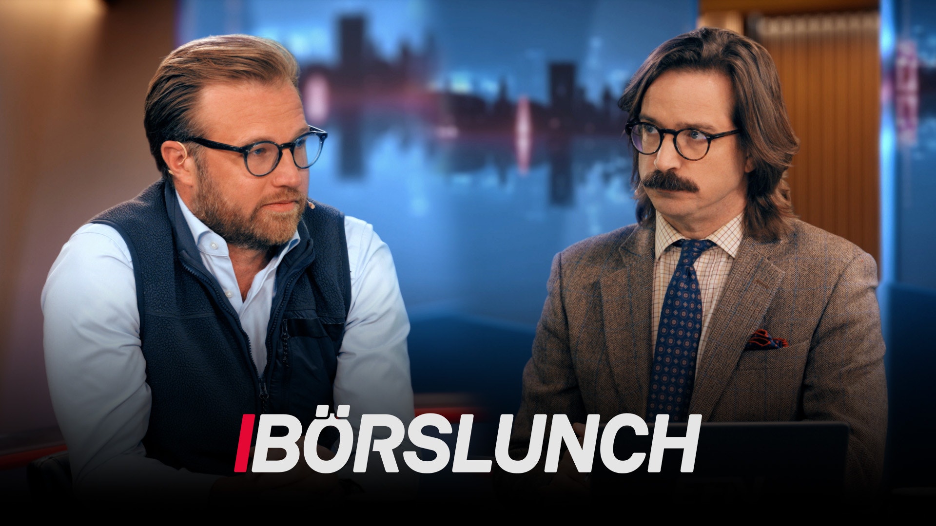 Två män i affärskläder diskuterar framför en stadshorisont.