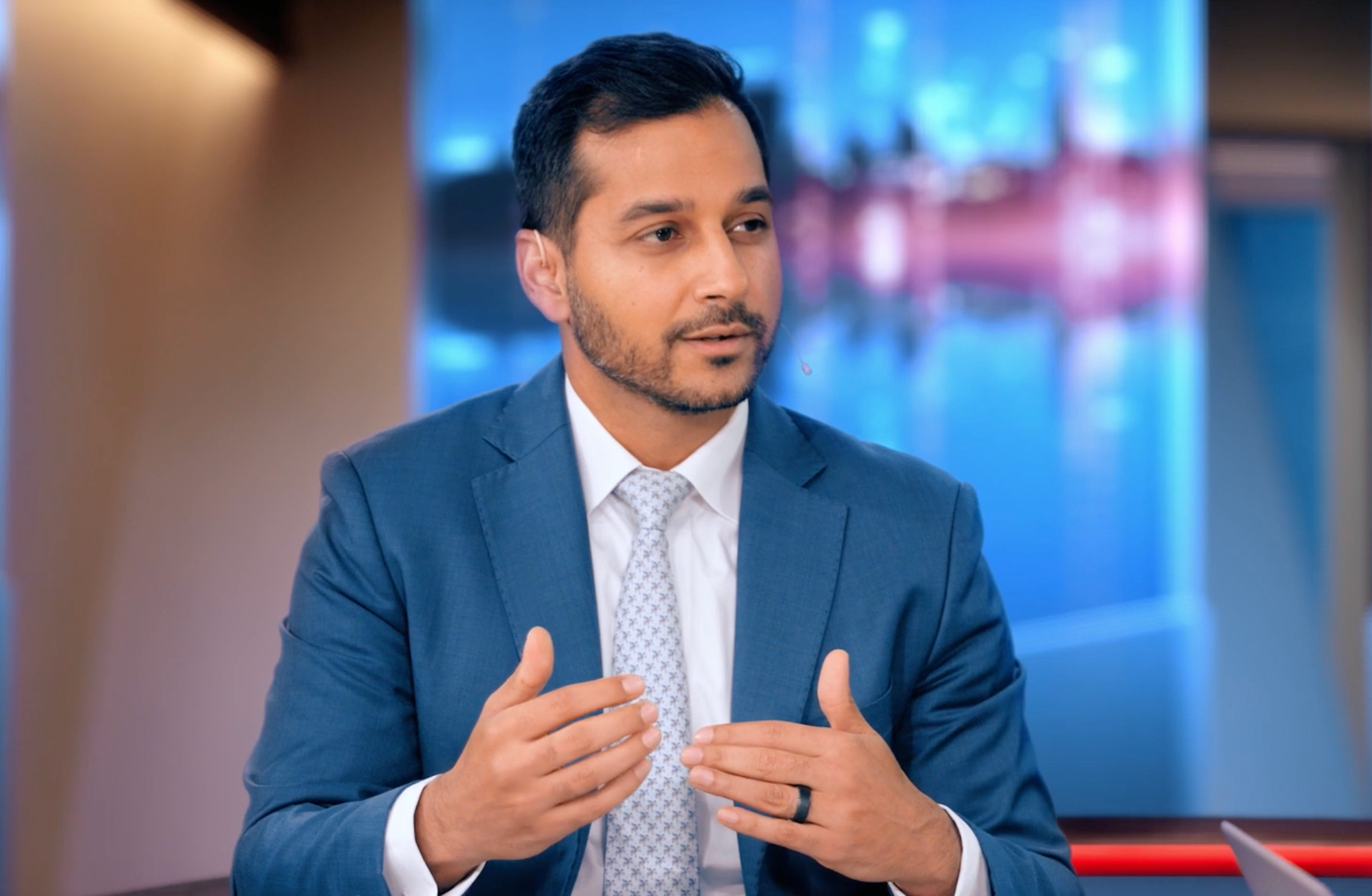 Man i kostym pratar och gestikulerar i en tv-studio.