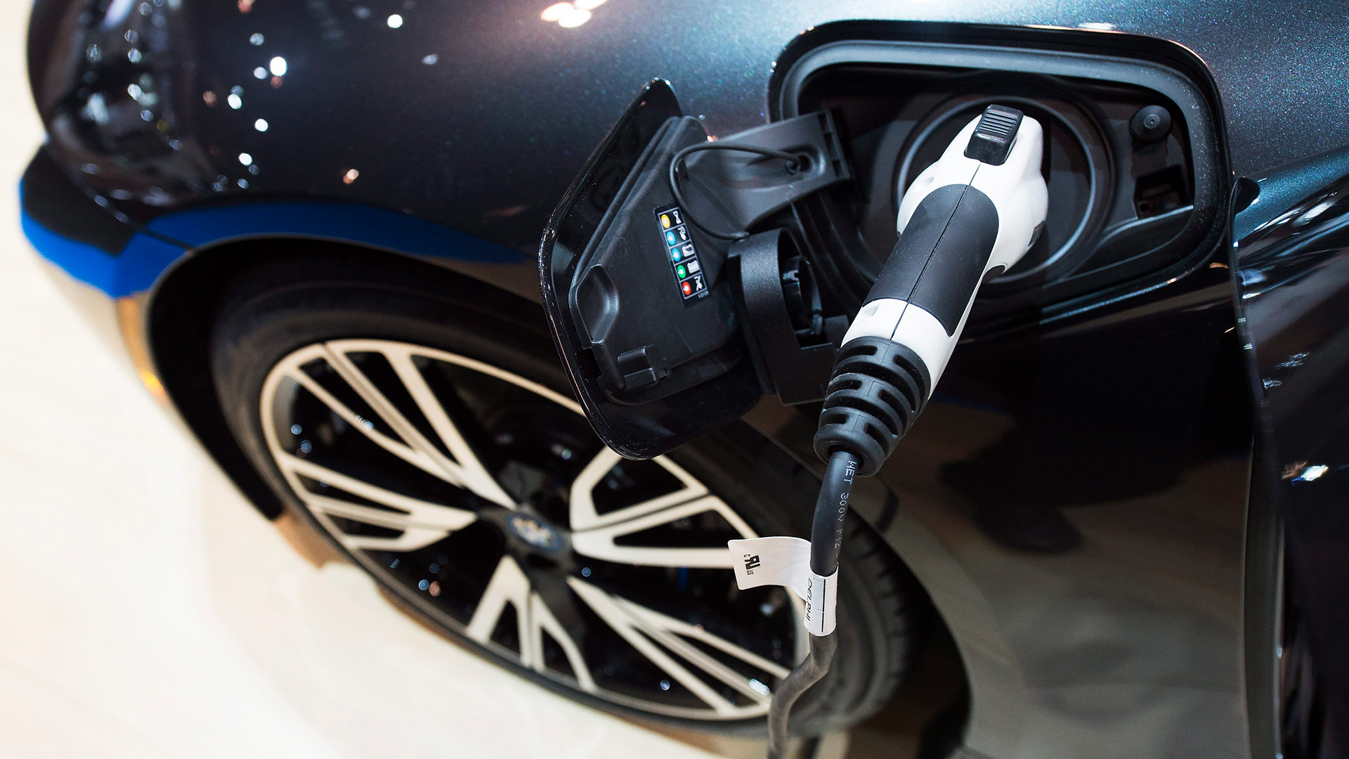 En svart BMW-elfordon ansluten till en laddningsstation med en vit och svart laddningskabel.