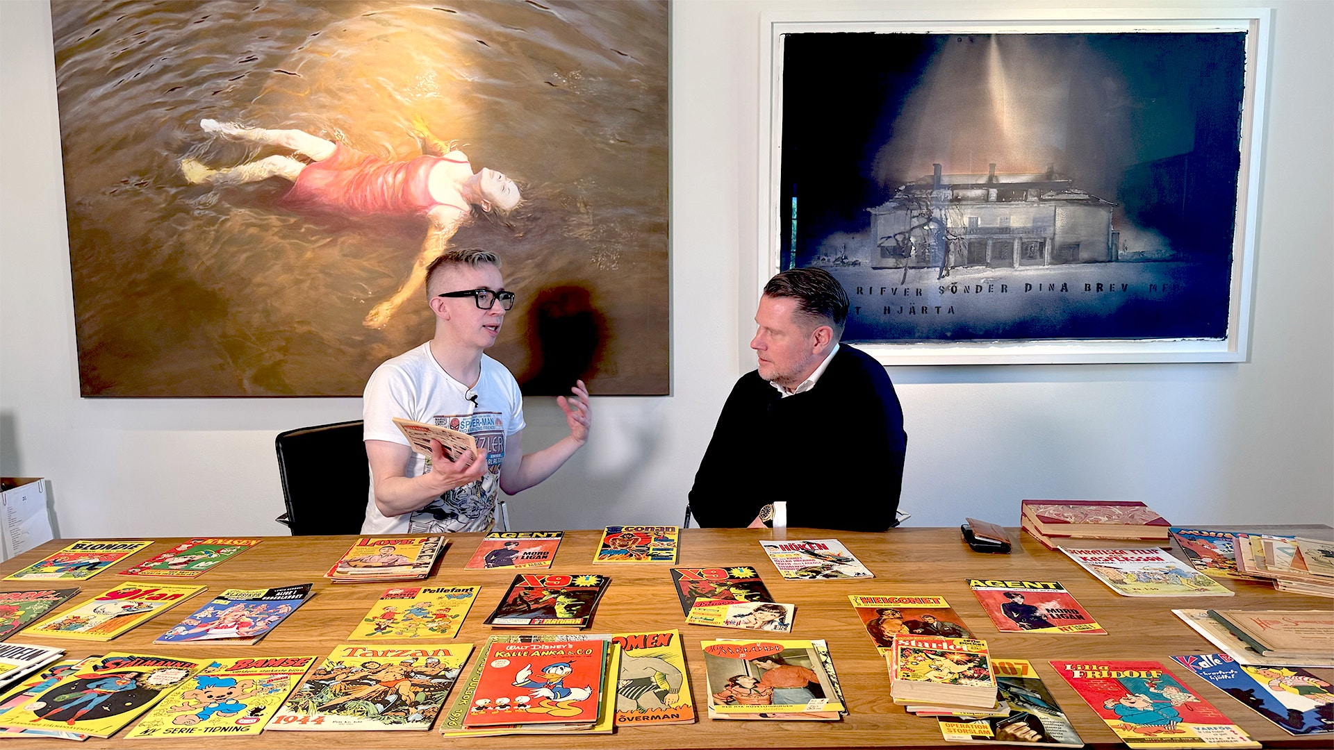 EFN:s Fredrik Strage och Embracers Lars Wingefors framför ett bord där Wingefors samling av serietidningar ligger.