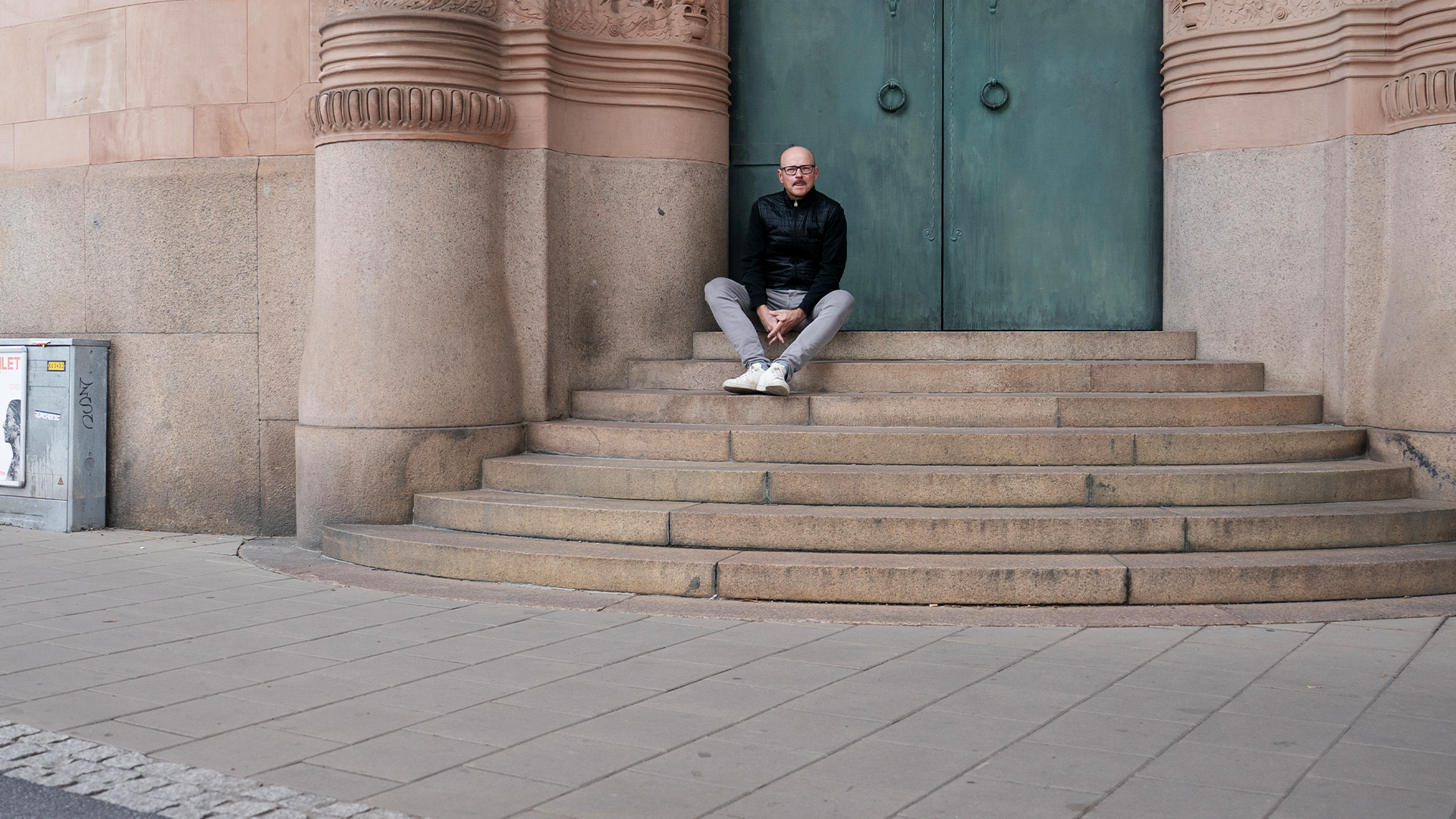 Pål Ahlsén sitter på en trappa upp till porten utanför Castellums kontor. 