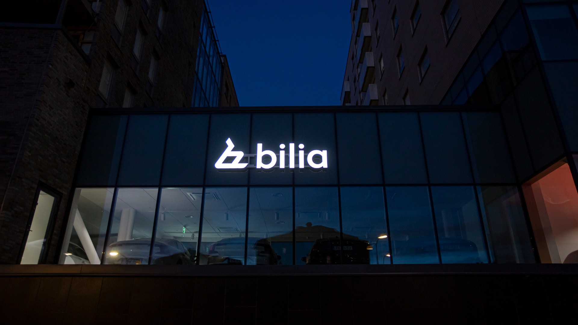 Bilia-logotyp på en modern byggnad belyst på kvällen