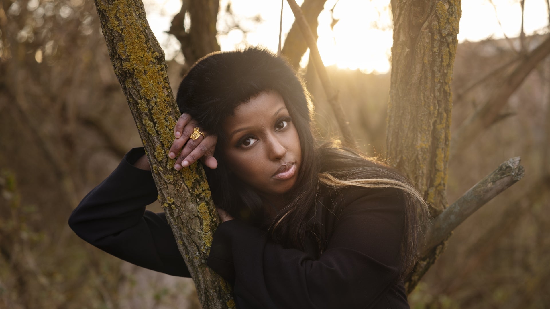 Porträtt av en kvinna i en skog med träd i bakgrunden