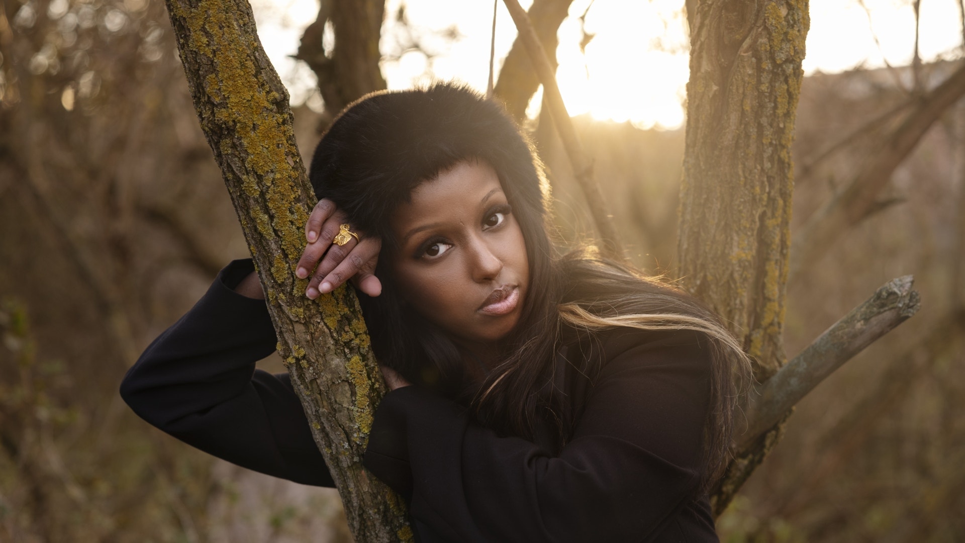 Porträtt av en kvinna i en skog med träd i bakgrunden