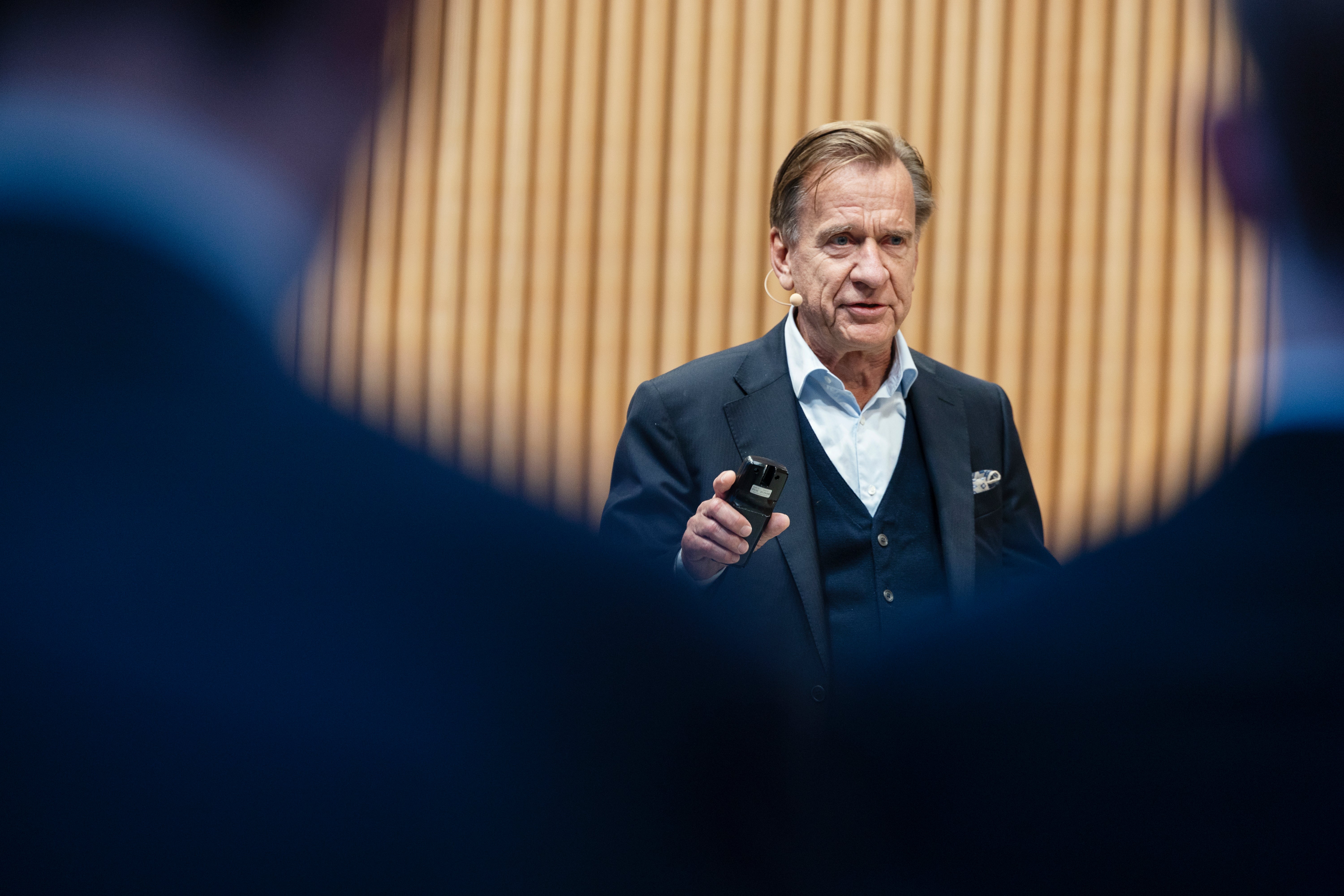 En man i kostym håller en presentation och pratar till en publik.