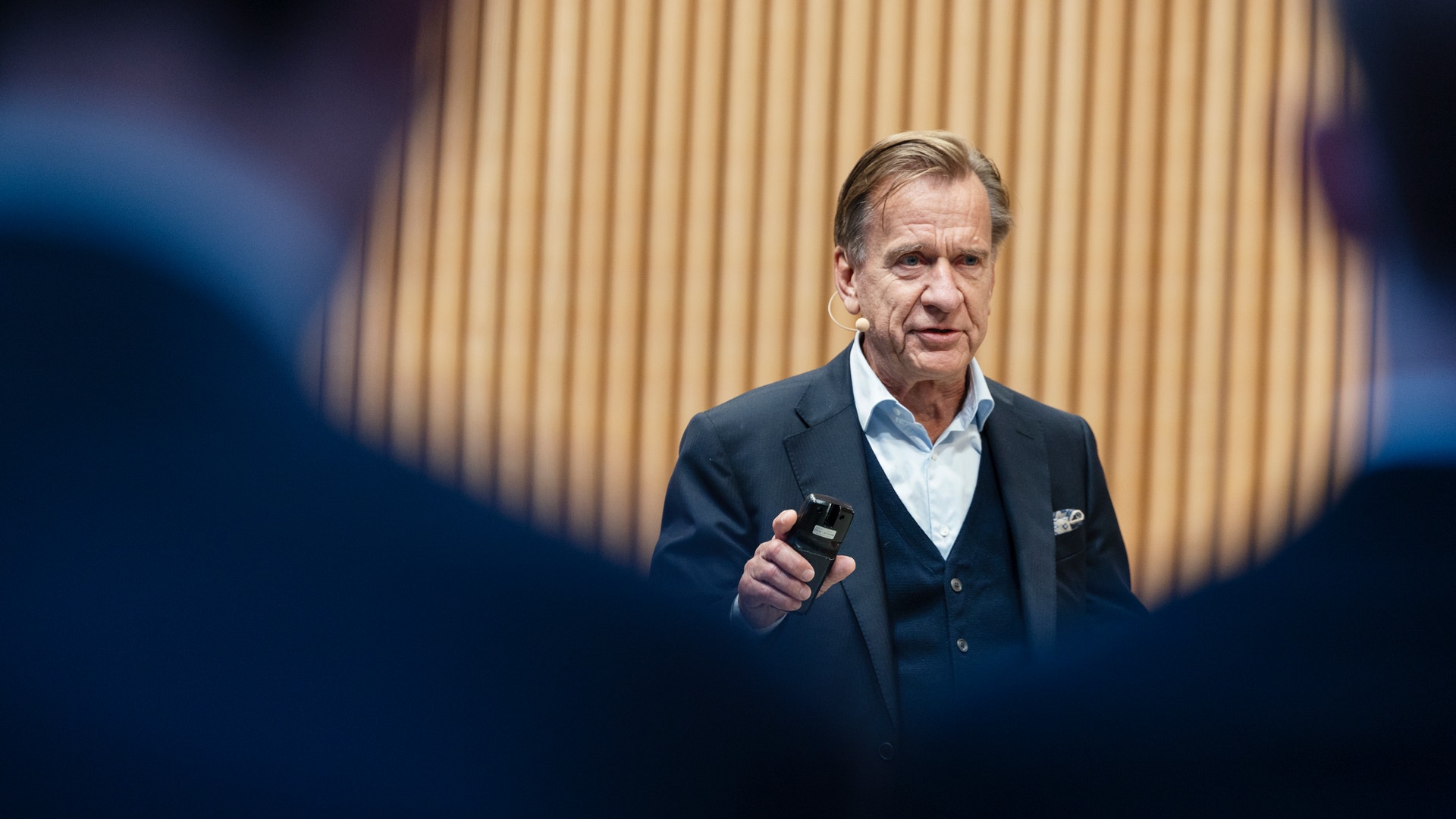En man i kostym håller en presentation och pratar till en publik.