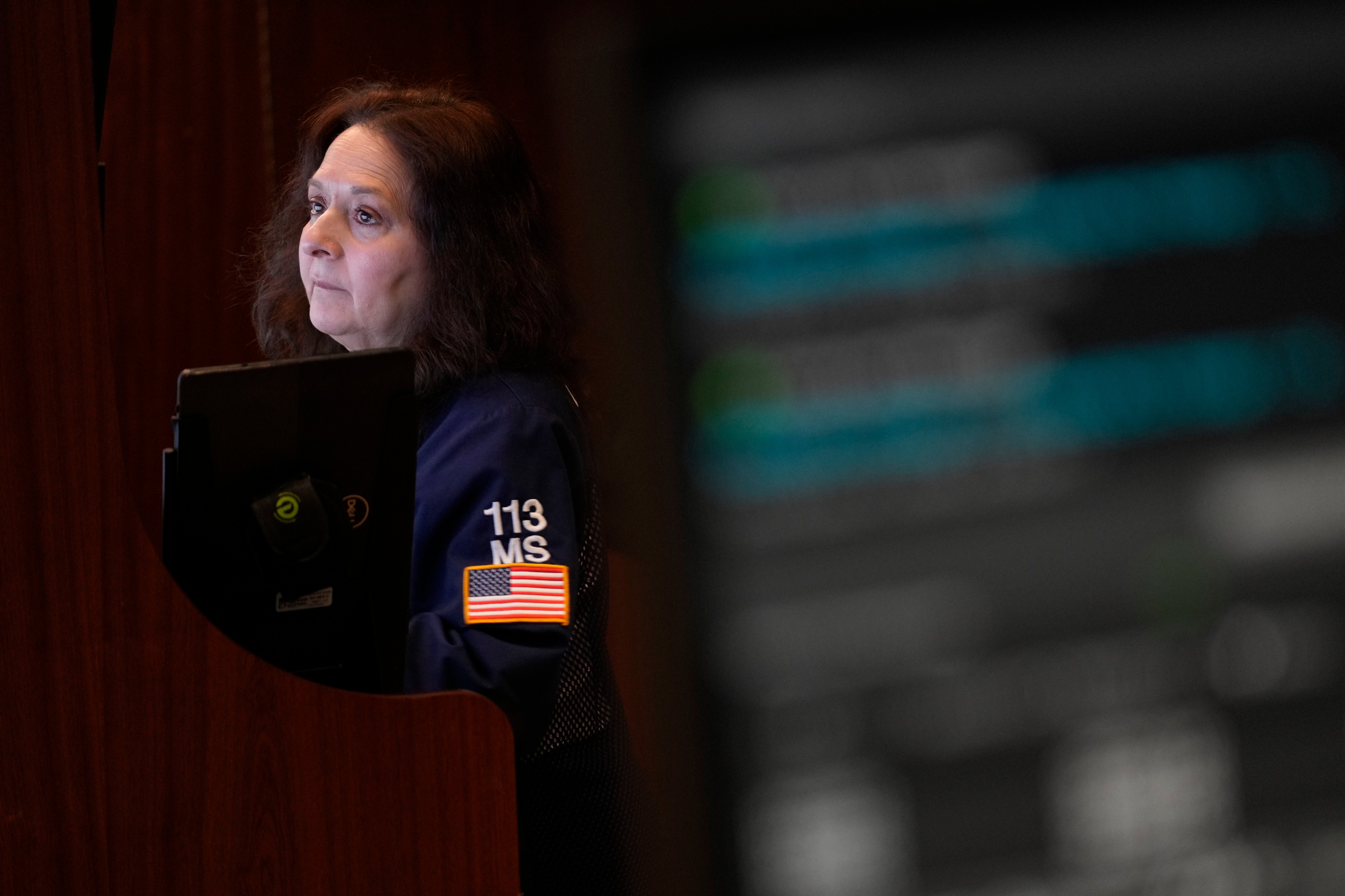 Person i mörkblå jacka håller en surfplatta och tittar åt sidan.