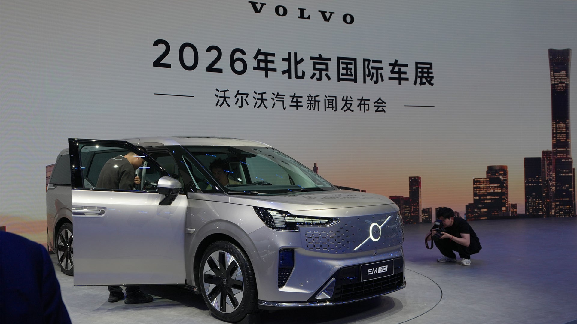 En silverfärgad Volvo-elbil visas på utställningsplattformen vid 2026 Beijing International Auto Show, med Pekings skyline i bakgrunden.