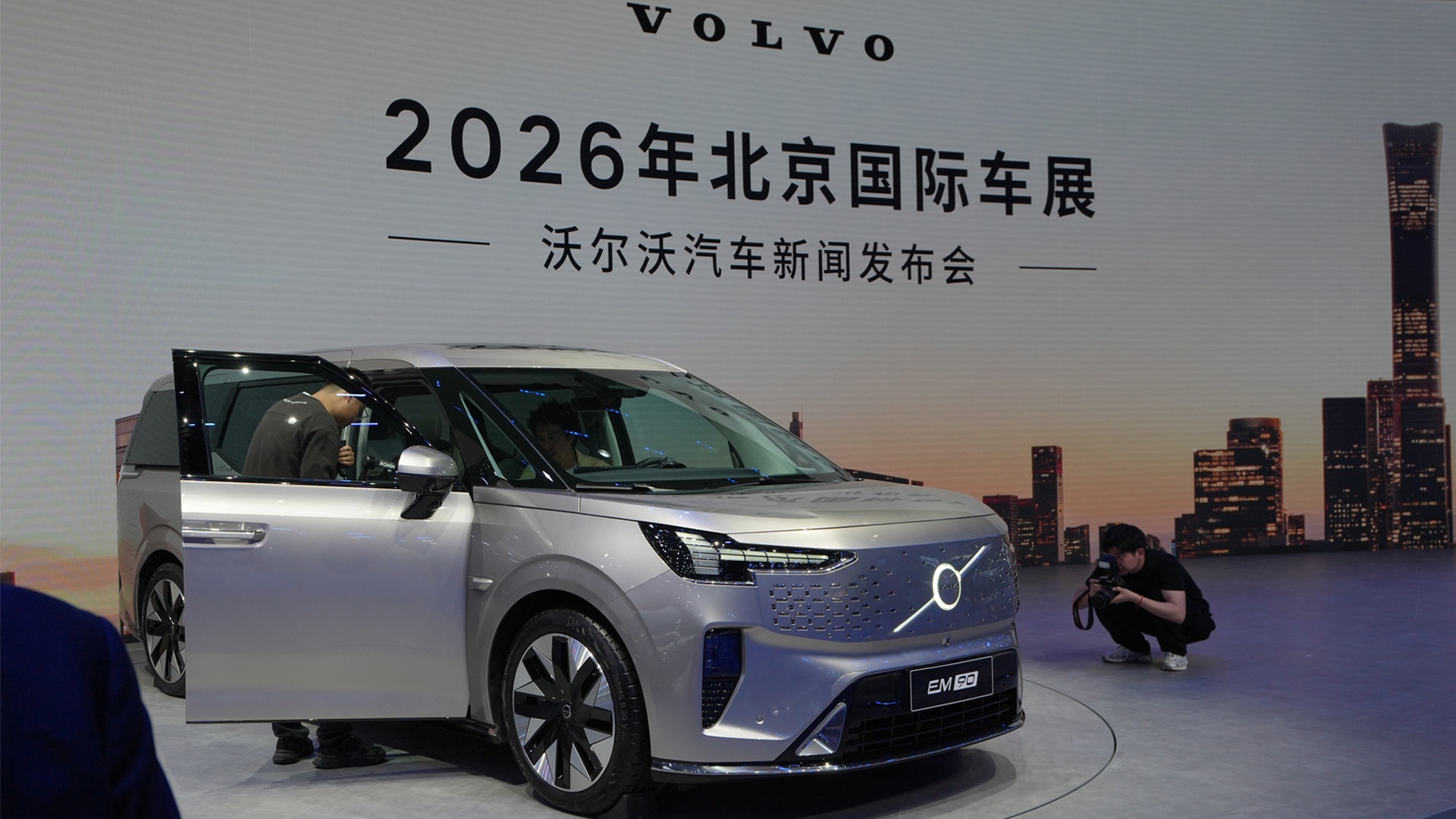 En silverfärgad Volvo-elbil visas på utställningsplattformen vid 2026 Beijing International Auto Show, med Pekings skyline i bakgrunden.