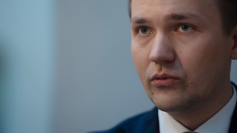 Porträtt av en man i blå kostym mot neutral bakgrund